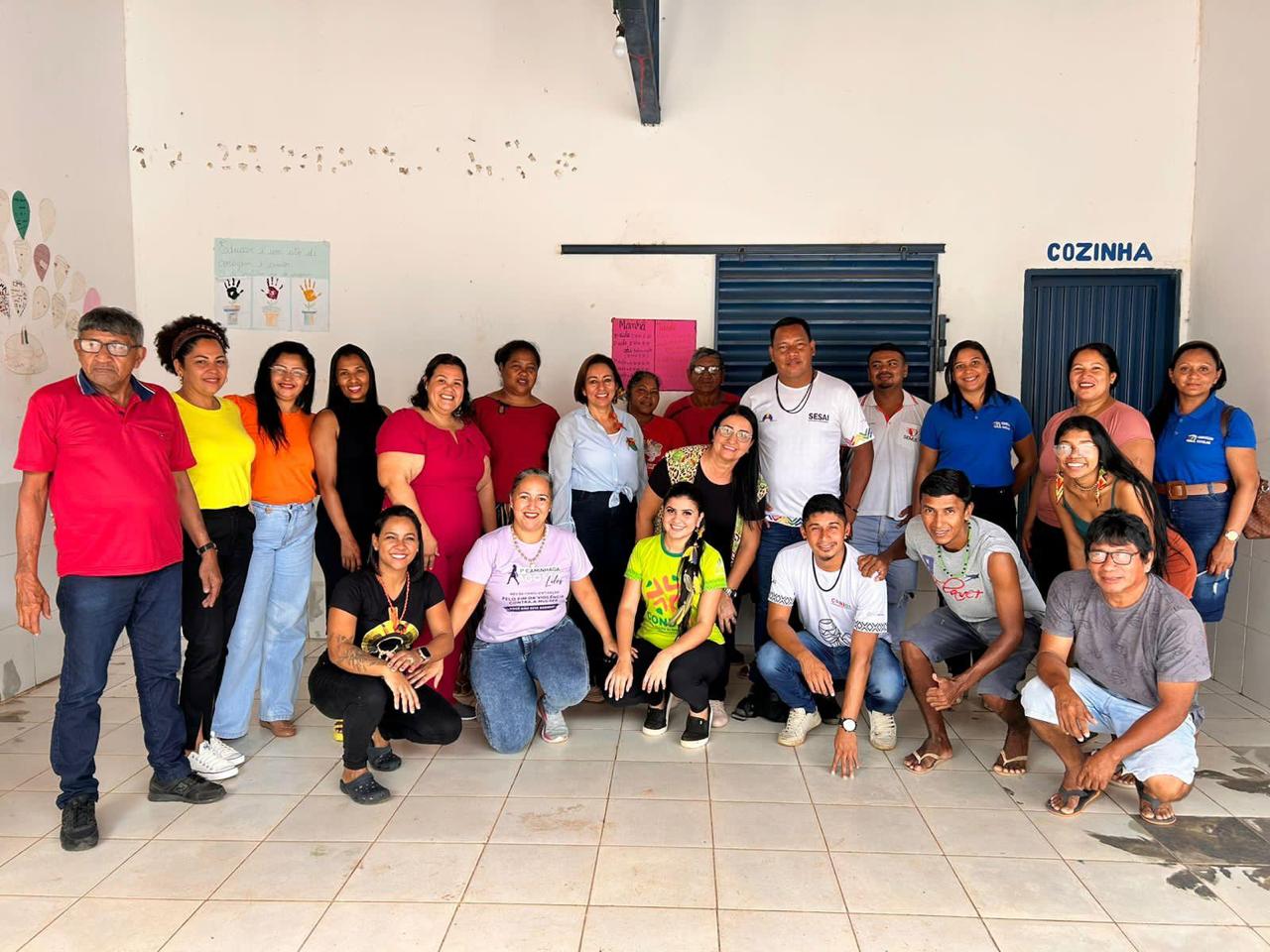 Vinte e duas pessoas com diferentes vestimenta, cores e gêneros posam para foto