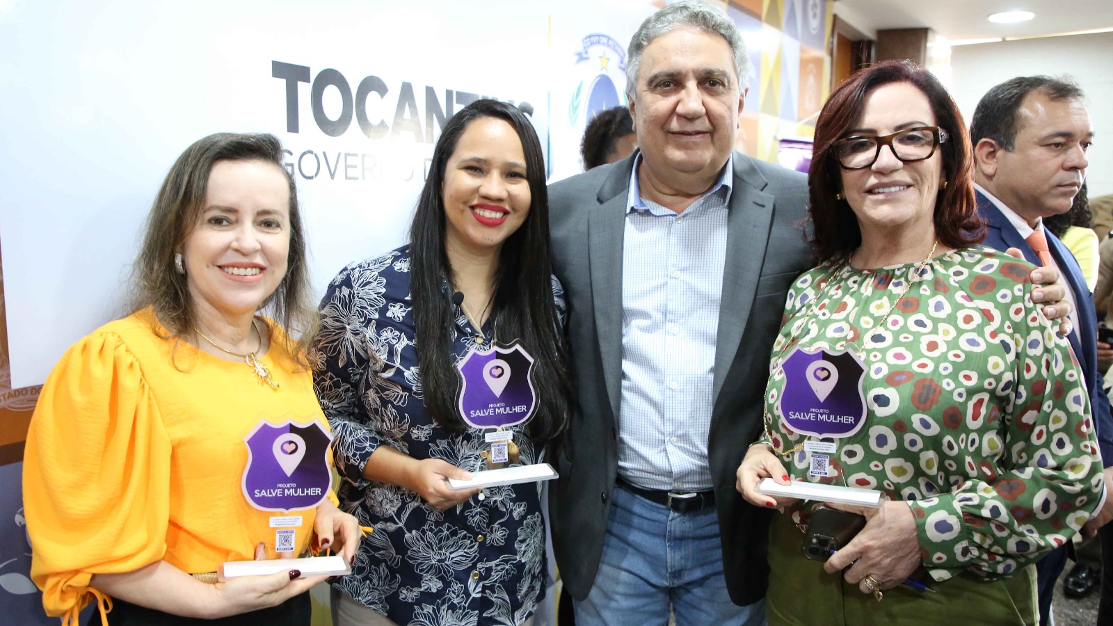 Desembargadora Etelvina Maria posando para foto segurando a logo do aplicativo Salva Mulher ao lado do vice-governador do Estado Laurez Moreira