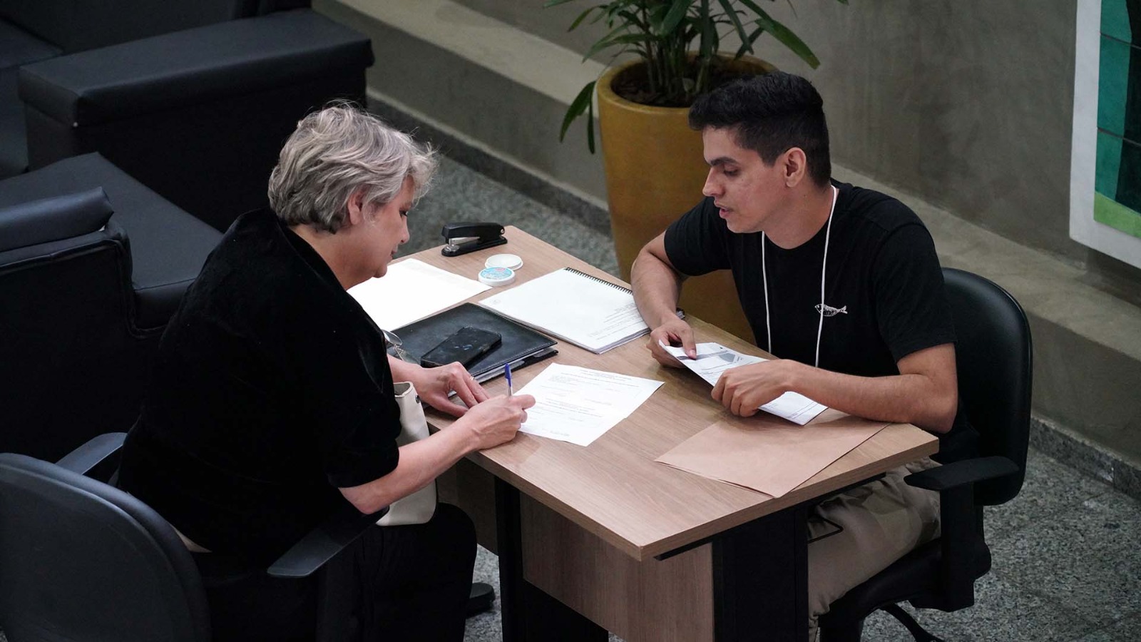 Mulher sentada em uma mesa realizando inscrição do concurso