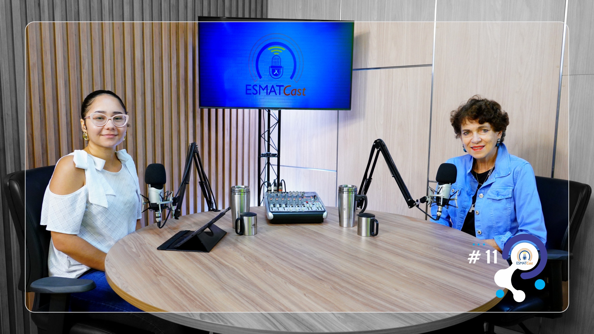 Jornalista da Esmat, Francielly Oliveira com a Solange Mata Machado, pós-doutora em Neurociência Aplicada aos Processos de Inovação e doutora e mestra em Inovação e Competitividade, sentadas em uma mesa redonda com uma tv ao centro da mesa com os dizeres "EsmatCast"