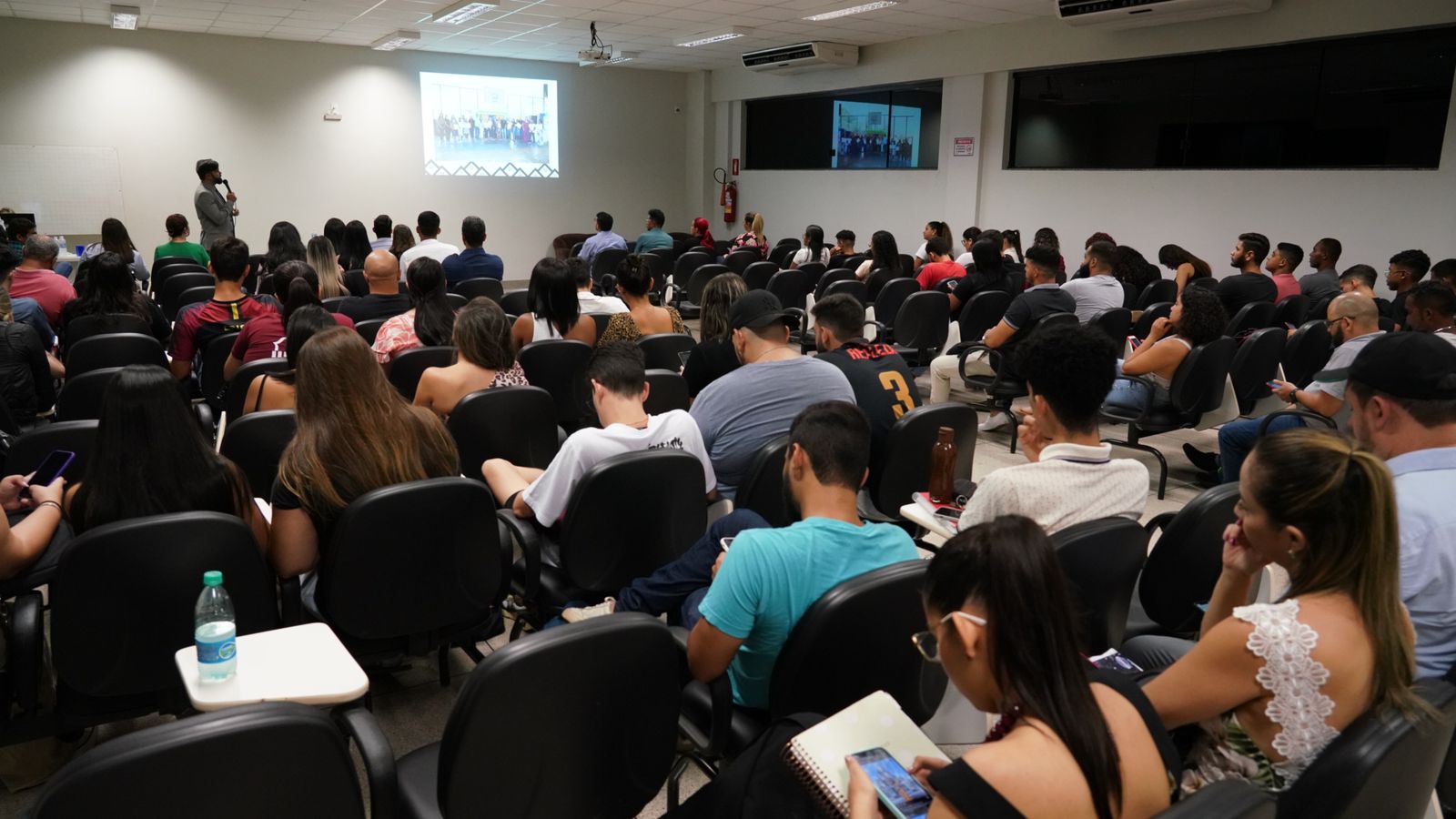 Alunos sentados reunidos em uma sala olhando atentamente ao slide apresentado pelo Juiz Welligton Magalhães