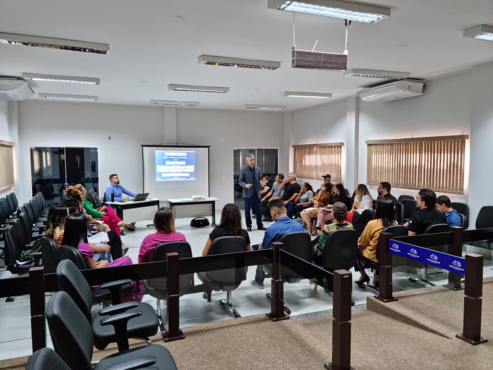 Pessoas reunidas em meia lua olhando atentamente ao slide que está sendo projetado