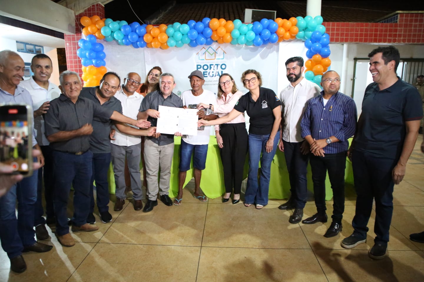 Servidores posando para foto junto moradores beneficiados com o título de propriedade a mostra