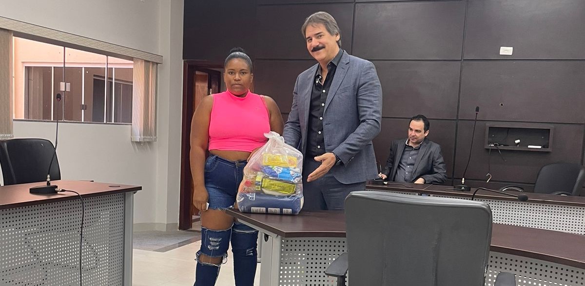 juiz ao lado de beneficiada segurando a cesta básica