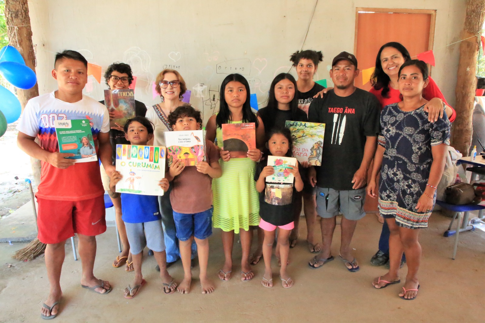 Indígenas beneficiados da arrecadação posando para foto com livro na mão