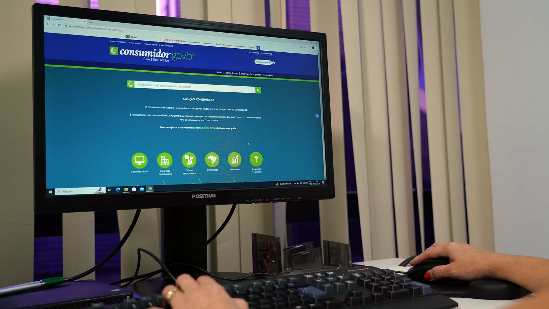 Maos de uma pessoa manuseando um computador com o site consumidor.gov.br aberto.
