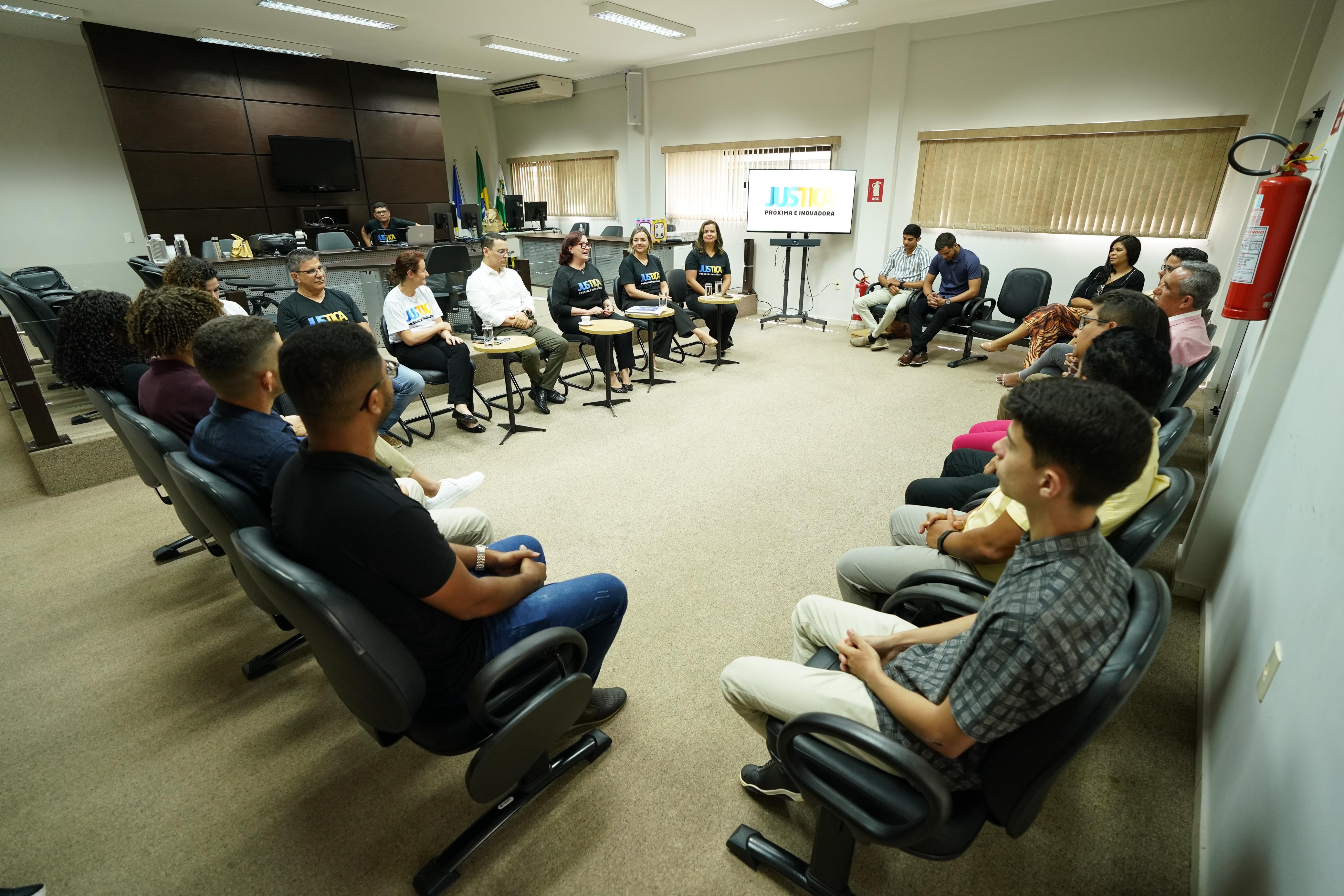 Grupo de pessoas reunidas promovendo interação e um logotipo visível sobre a justiça mais próxima e inovadora.