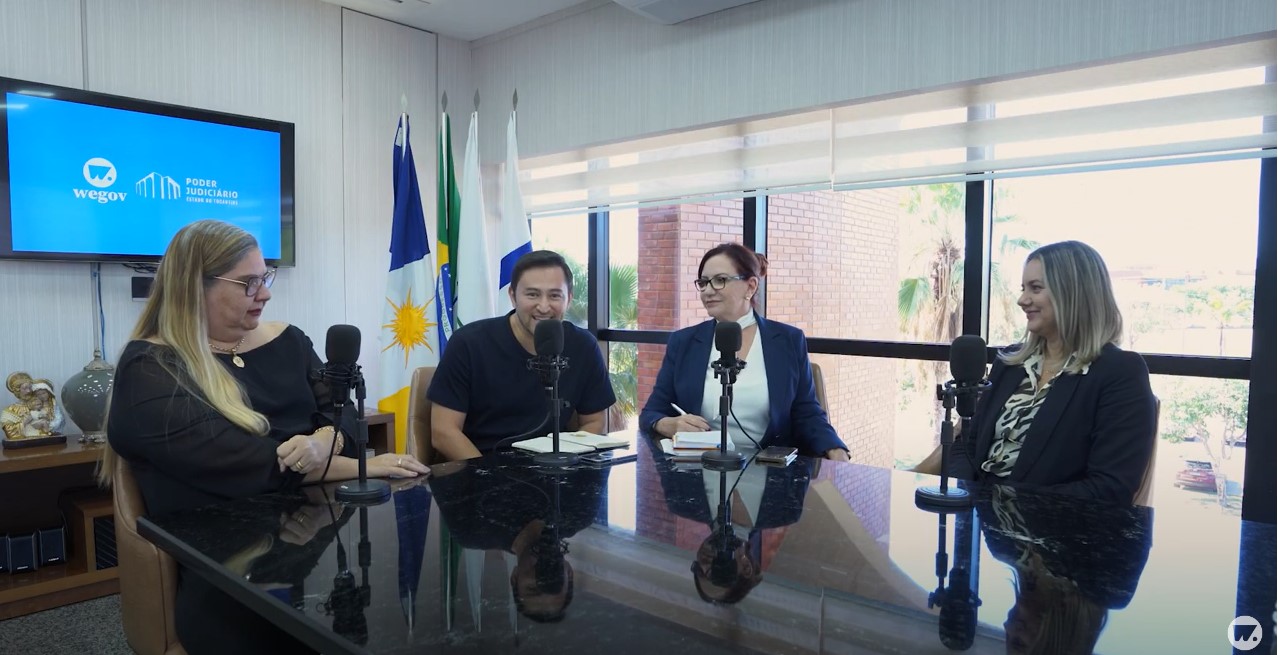 Imagem colorida mostra quatro pessoas em uma mesa, durante entrevista para Podcast