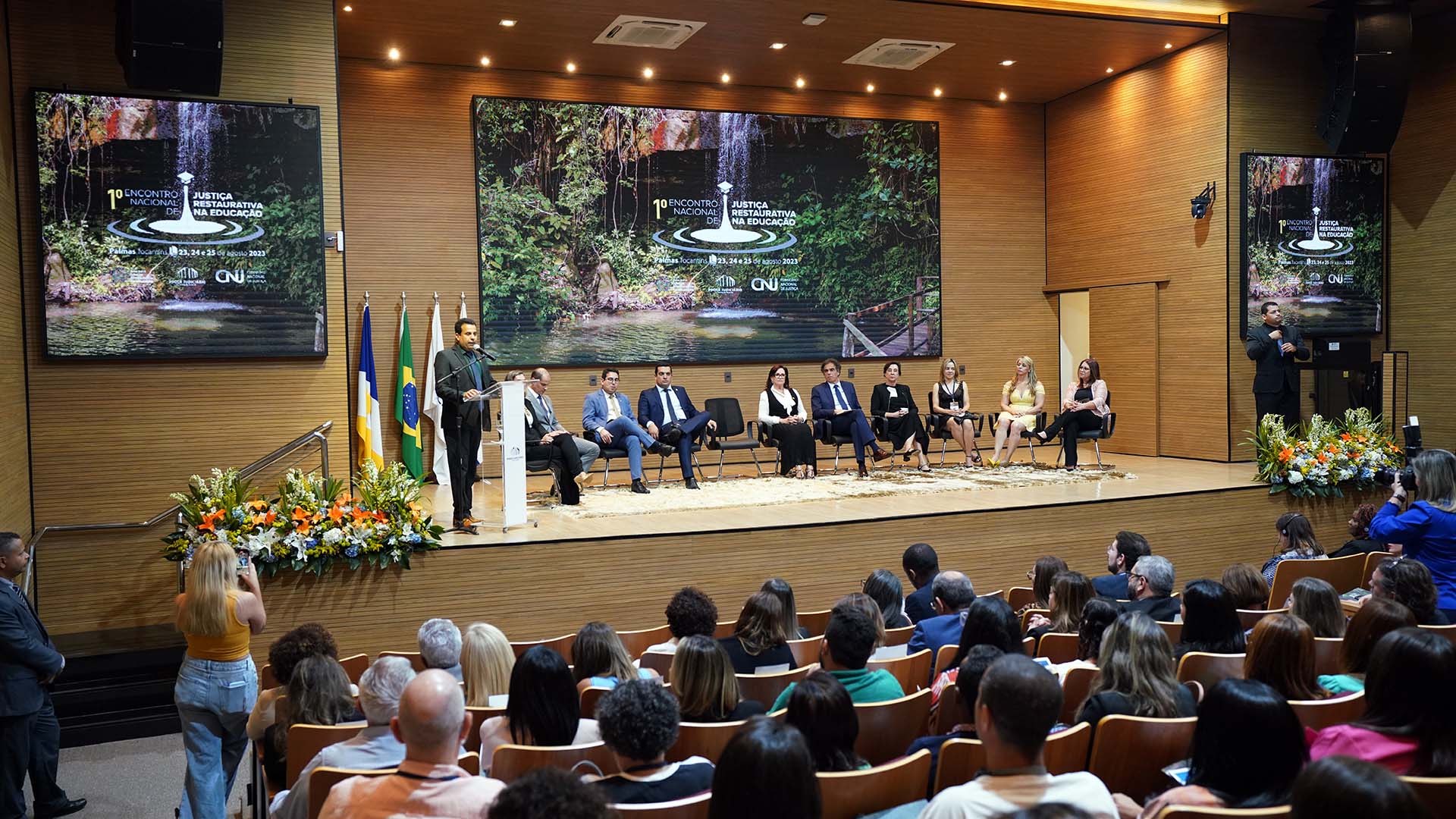 Presidente do TJTO, vestida preto, fala no púlpito para participantes do evento