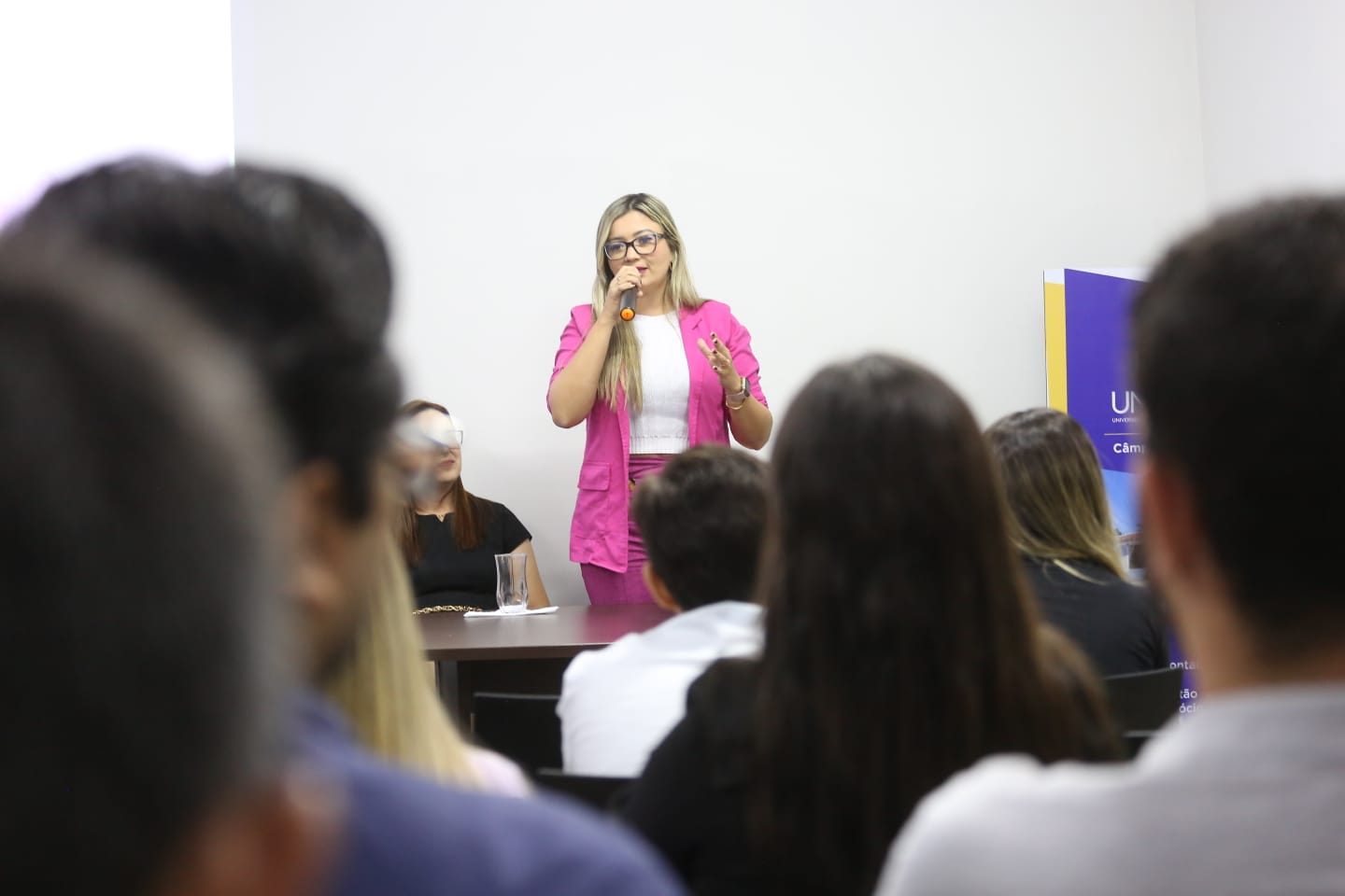 Mulher loira usando rosa fala para plateia 