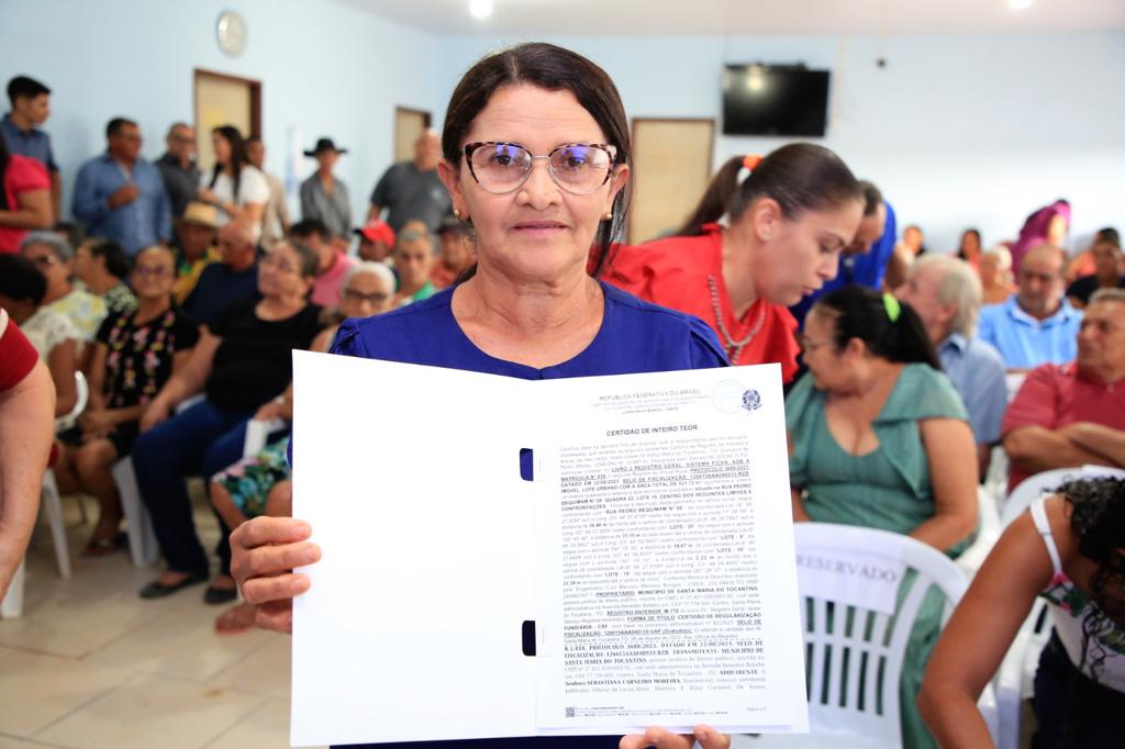 Beneficiada com título de propriedade em mãos posando para foto