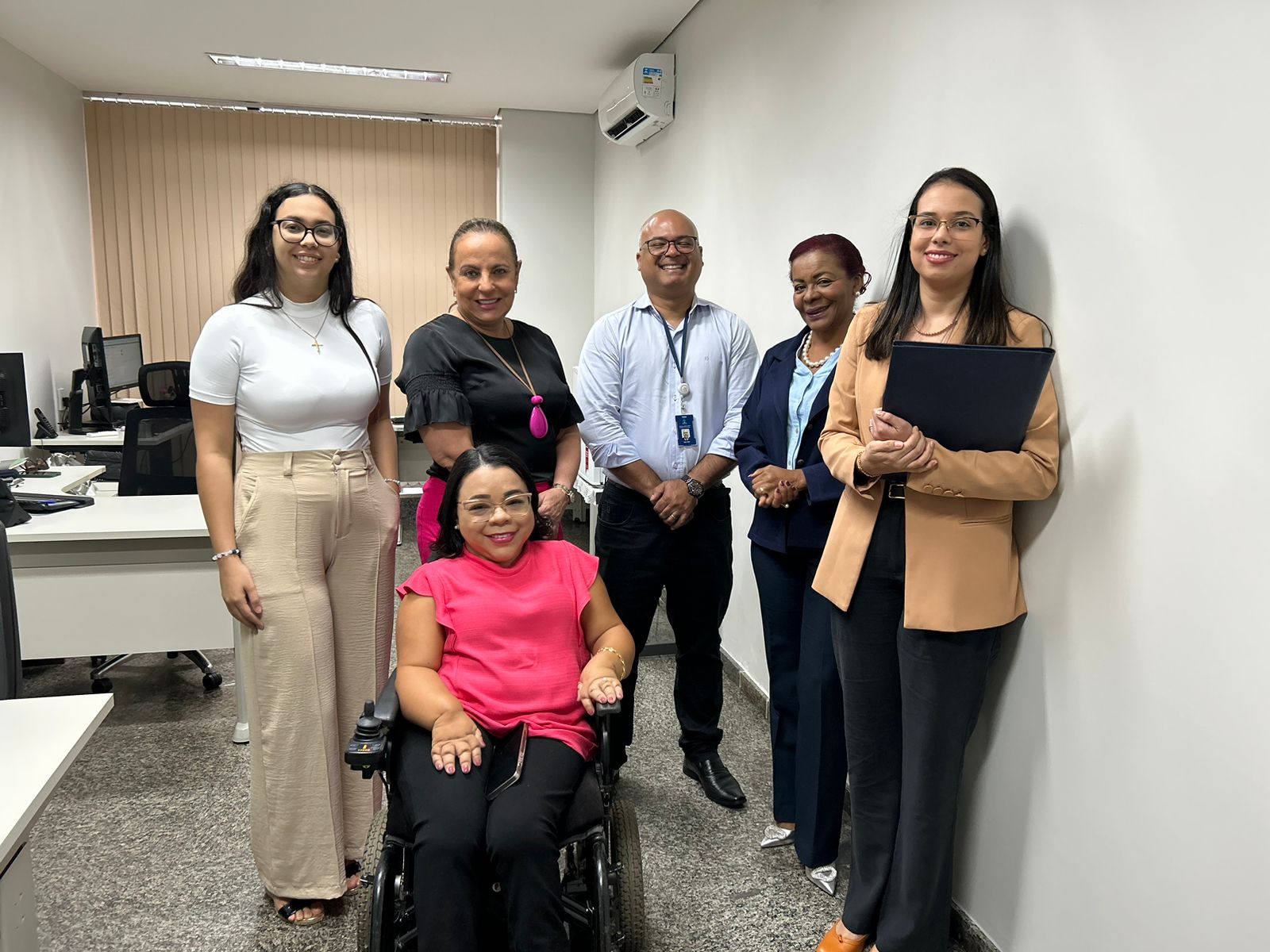 pessoas em pé junto com uma pessoa com deficiência em cadeiras de rodas posando para foto