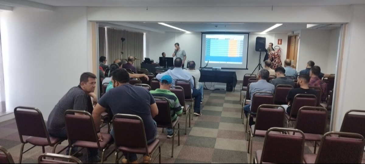 participantes do leilão assistem ao leiloeiro do TJ que está ao lado da tela de projeção ao fundo