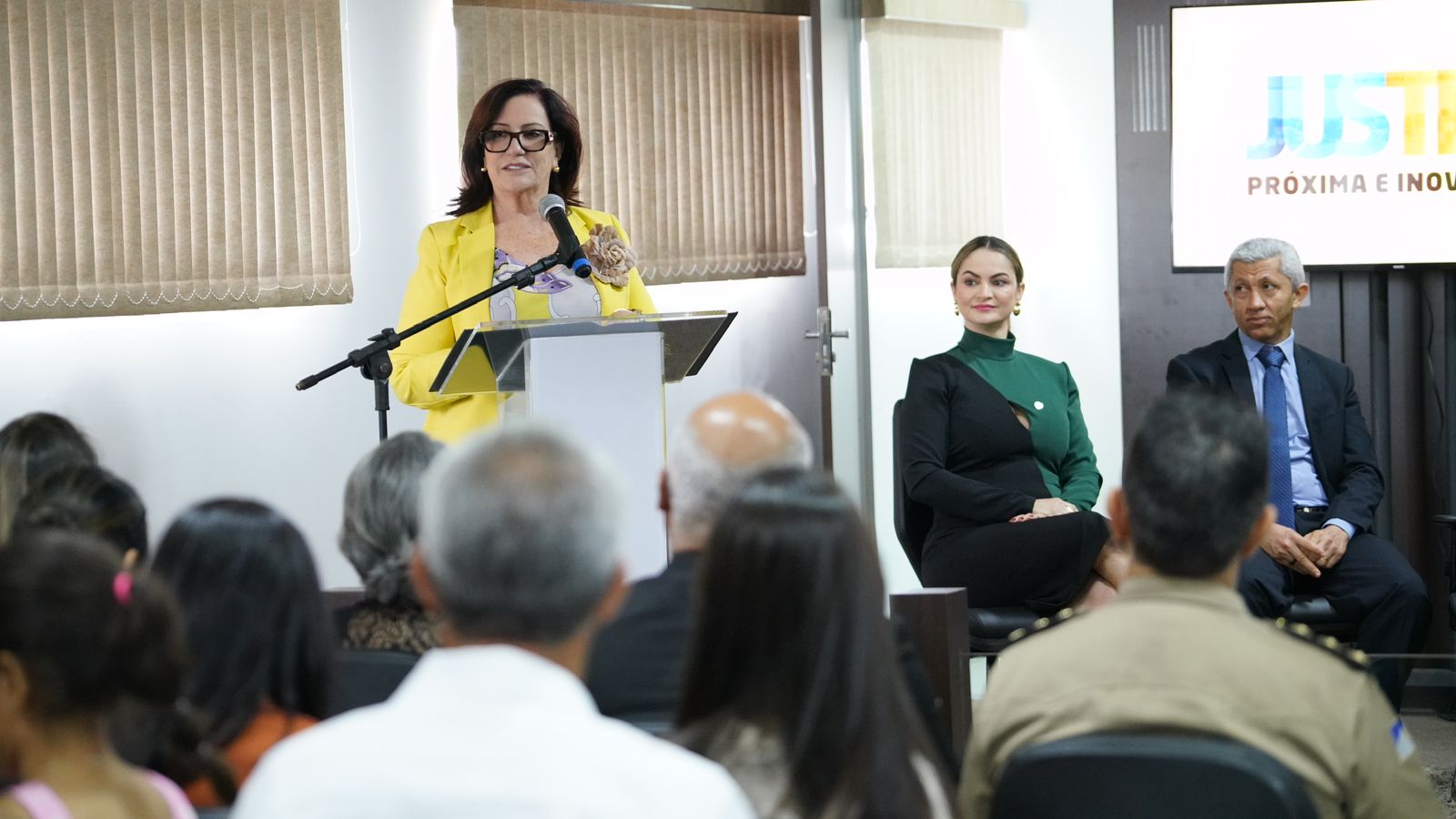 Fotografia colorida mostra a presidente do TJTO se pronunciando em uma tribuna. Ela usa amarelo 