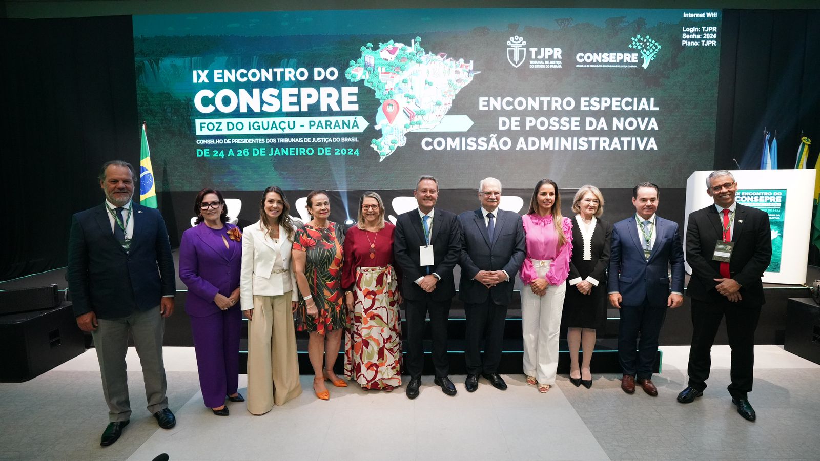 Foto com pessoas em pé, com roupas coloridas e ao fundo um banner do Consepre