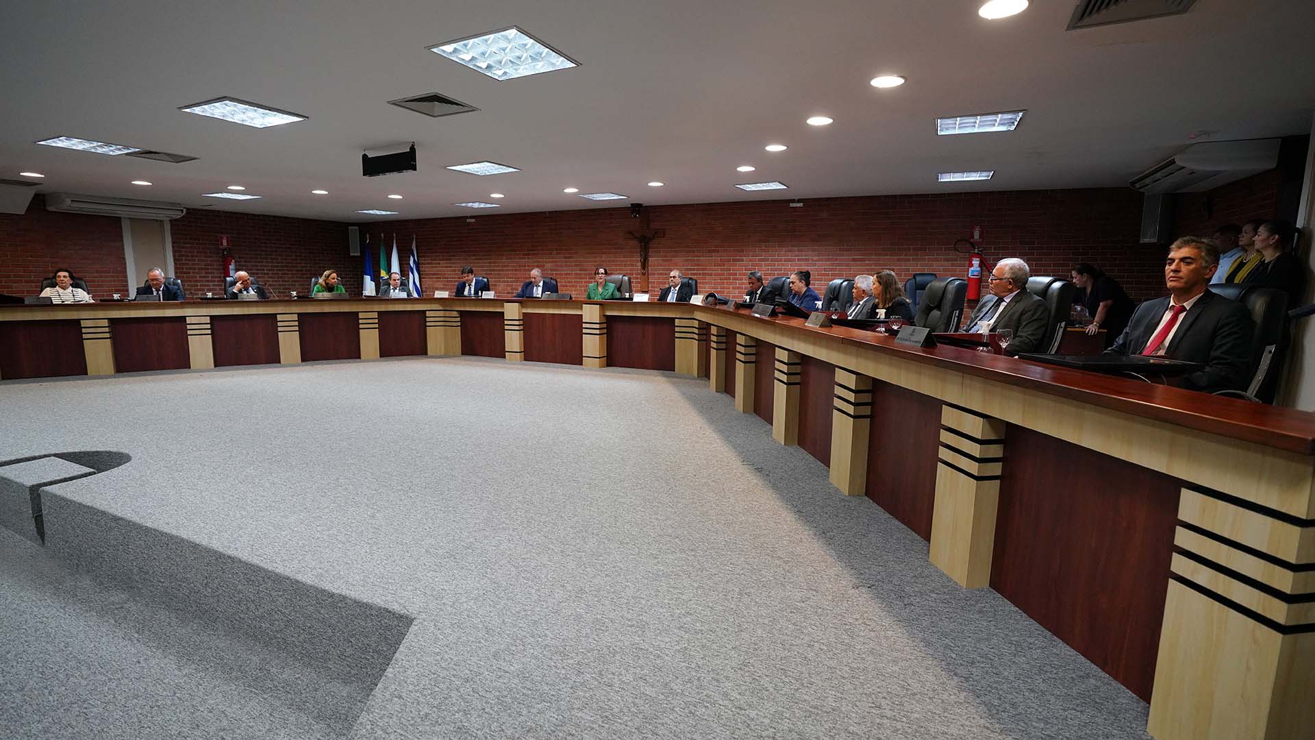 Foto aberta mostra várias pessoas sentadas atrás de mesa de madeira no Salão do Tribunal do Pleno do TJTO