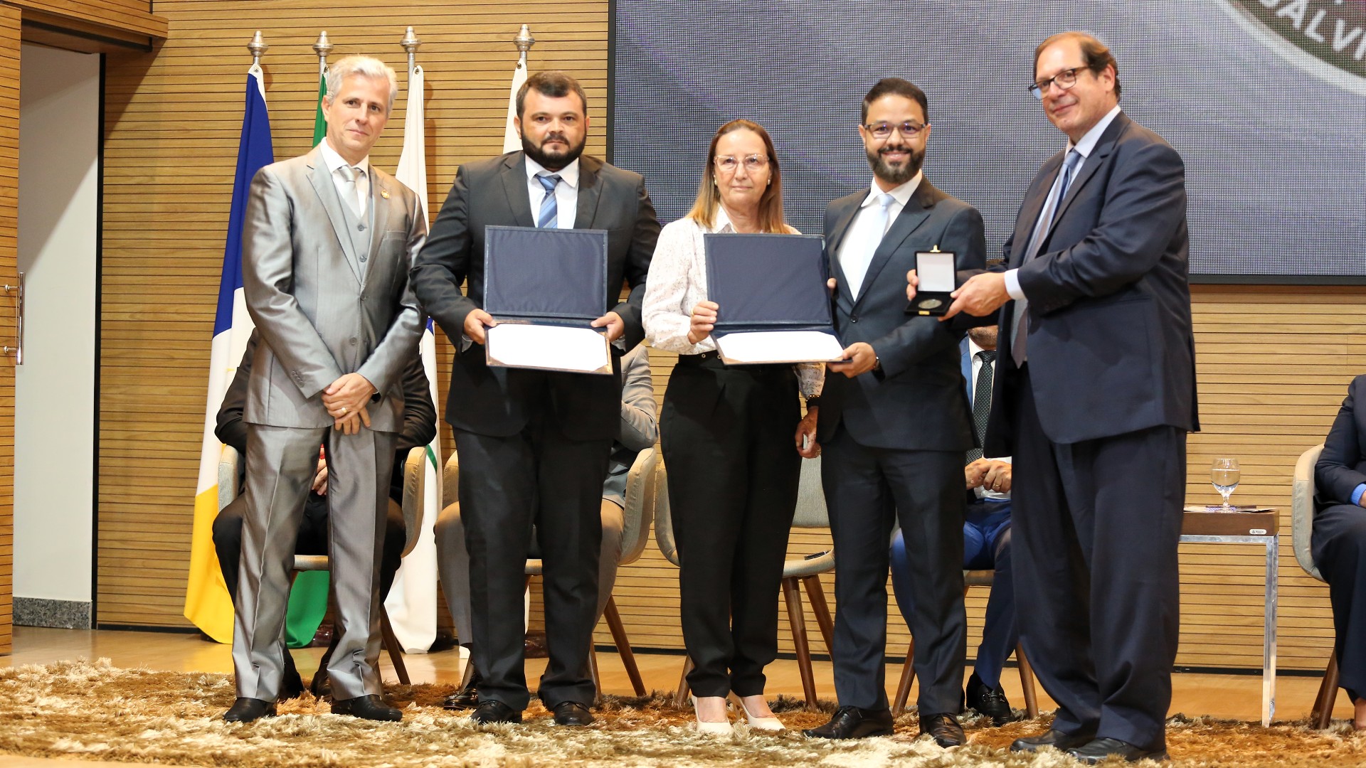 Fotografia colorida de magistrados e servidores do primeiro grau de jurisdição recebendo o prêmio de reconhecimento de gestão judiciária 