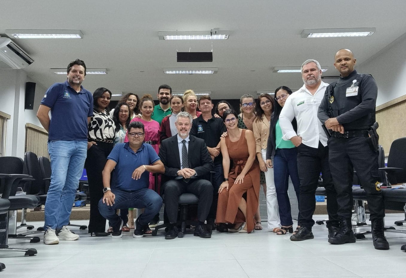 Juiz Ricardo Gagliardi (ao centro), cabelos e barba grisalhos, está sentado de terno escuro e camisa branca, ao lado da equipe da comarca