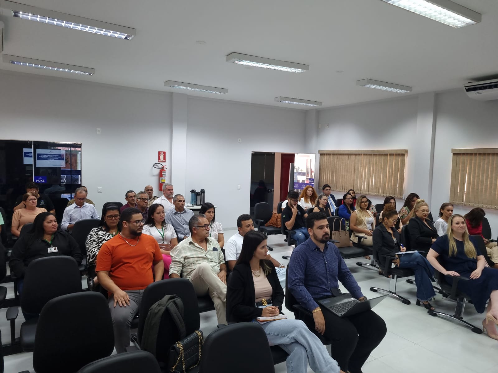 Várias pessoas sentada em um auditório participando de uma reunião