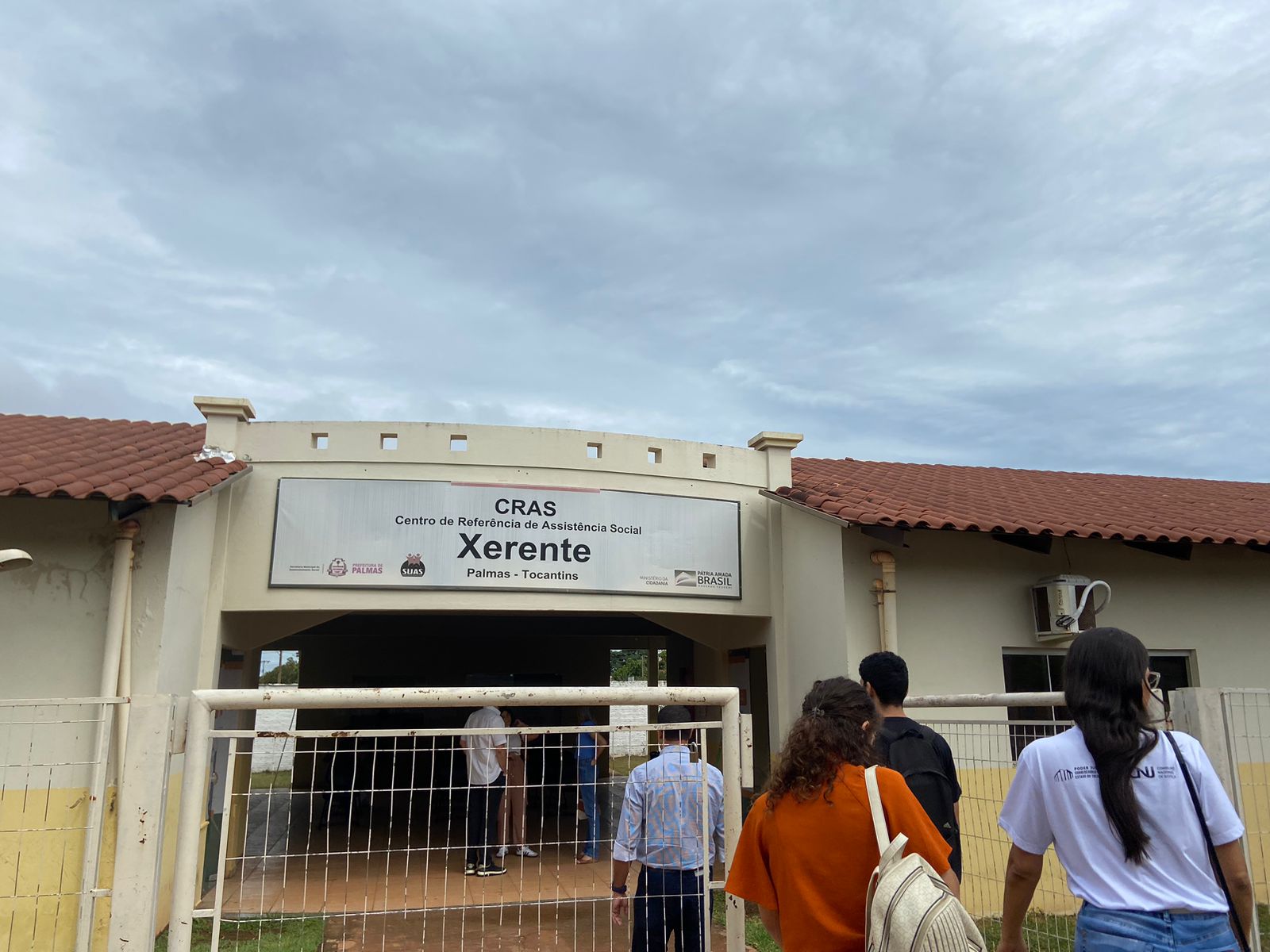Fotografia colorida da fachada do CRAS Xerente, onde pessoas estão entrando dentro da instituição 