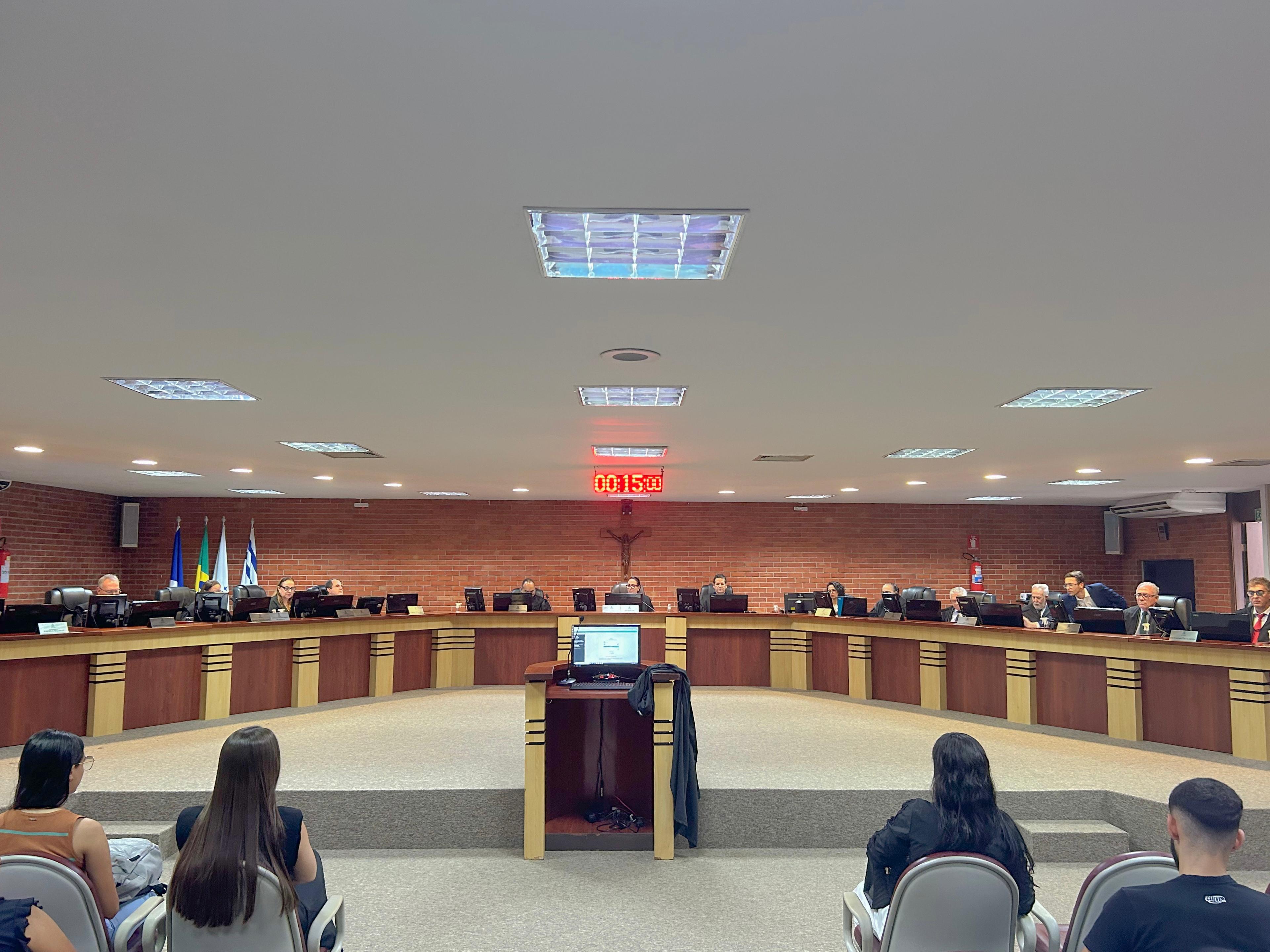 Sessão do Tribunal Pleno com os desembargadores dispostos em seus assentos e visão do público, por trás, e da tribuna de sustentação oral