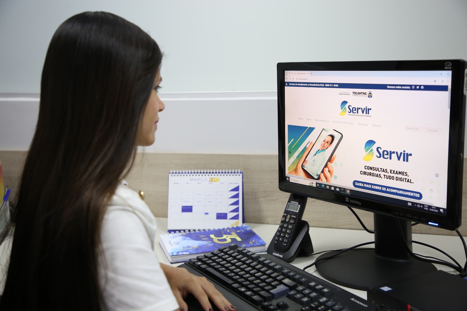 mulher sentada ao computador acessa a pagina do servir