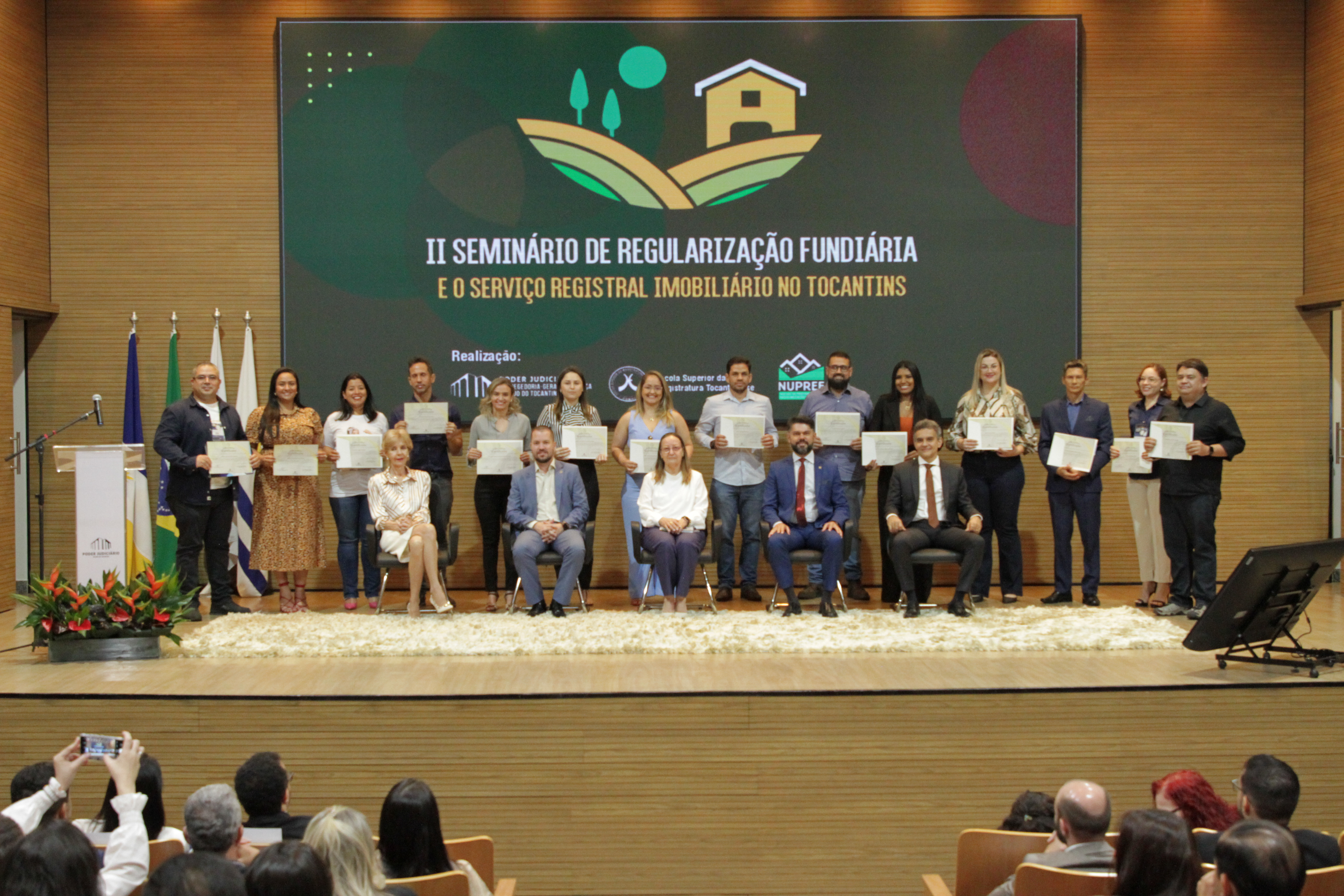 Fotografia colorida que mostram várias pessoas posando para a foto em auditório 