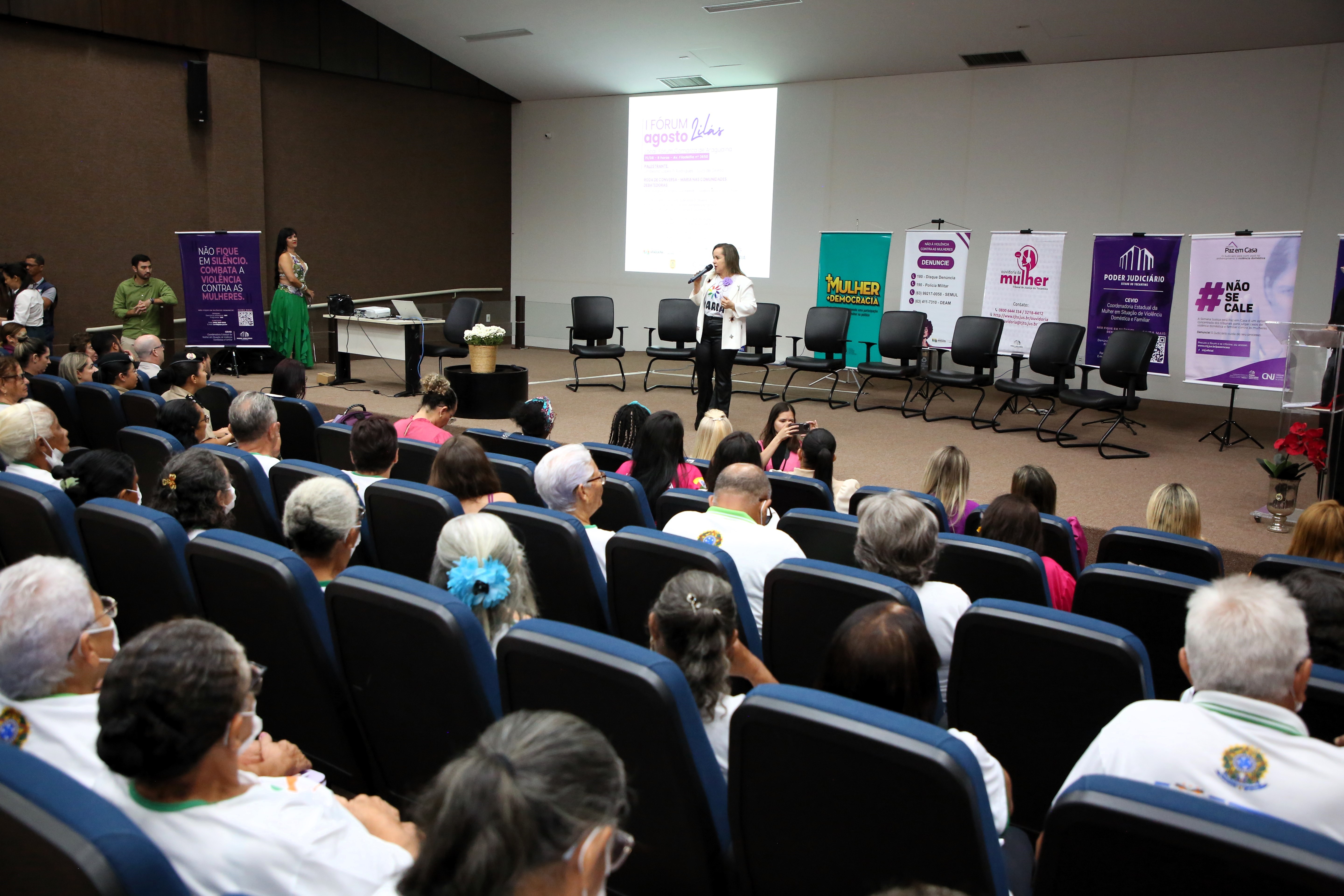 Auditório lotado e ao fundo, no palco, a juíza Cirlene falando ao microfone