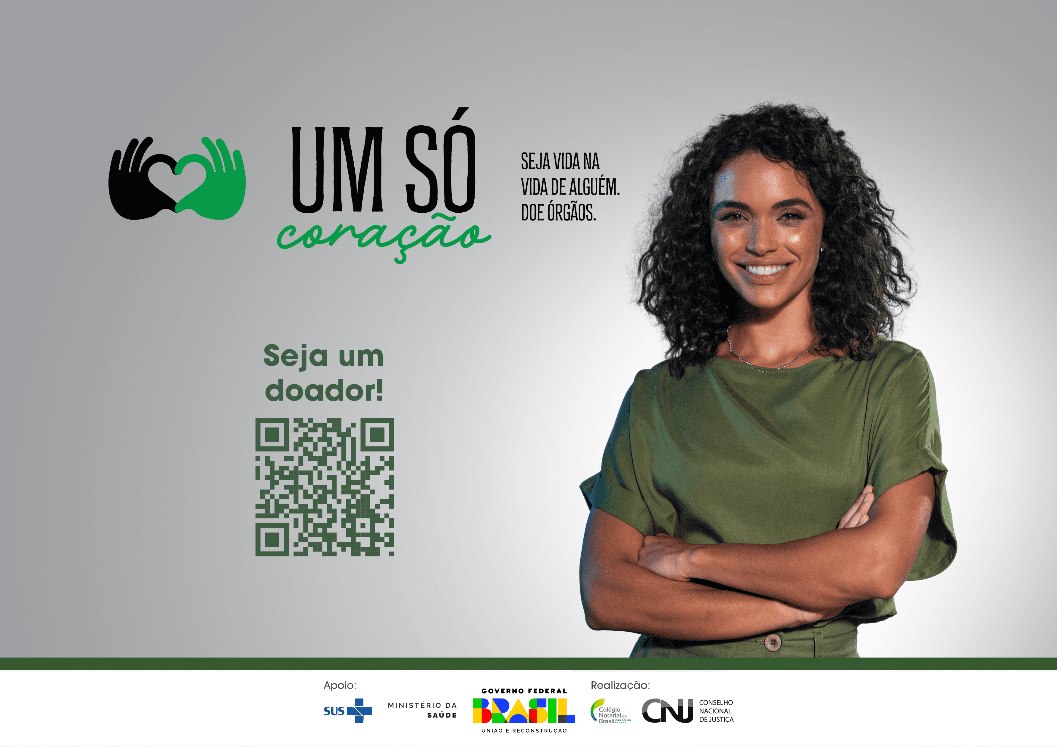Banner que mostra uma mulher negra de braços cruzados, vestindo verde, com uma frase ao fundo "Um só coração"