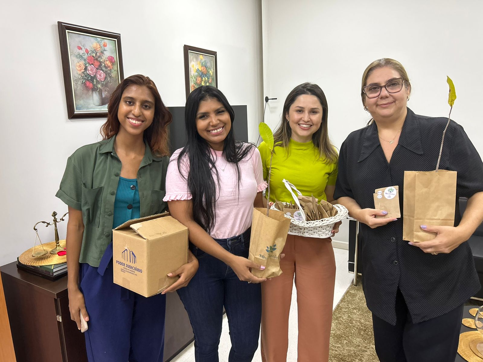 Mulheres em pé segurando mudas de árvores em ação comemorativa do Dia da Árvore