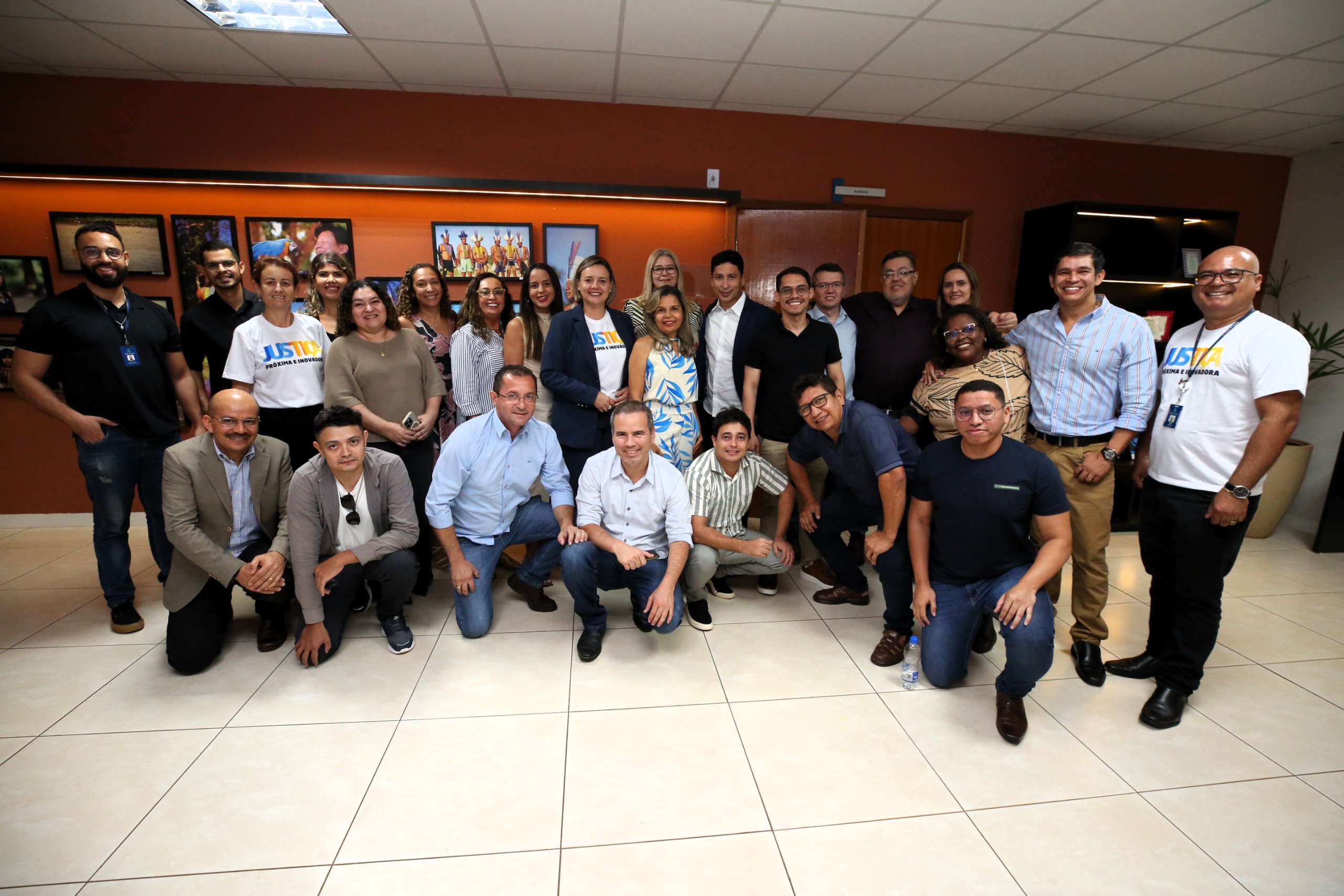 Imagem com várias pessoas em pé, com roupas de diversas cores; eles posam para a foto