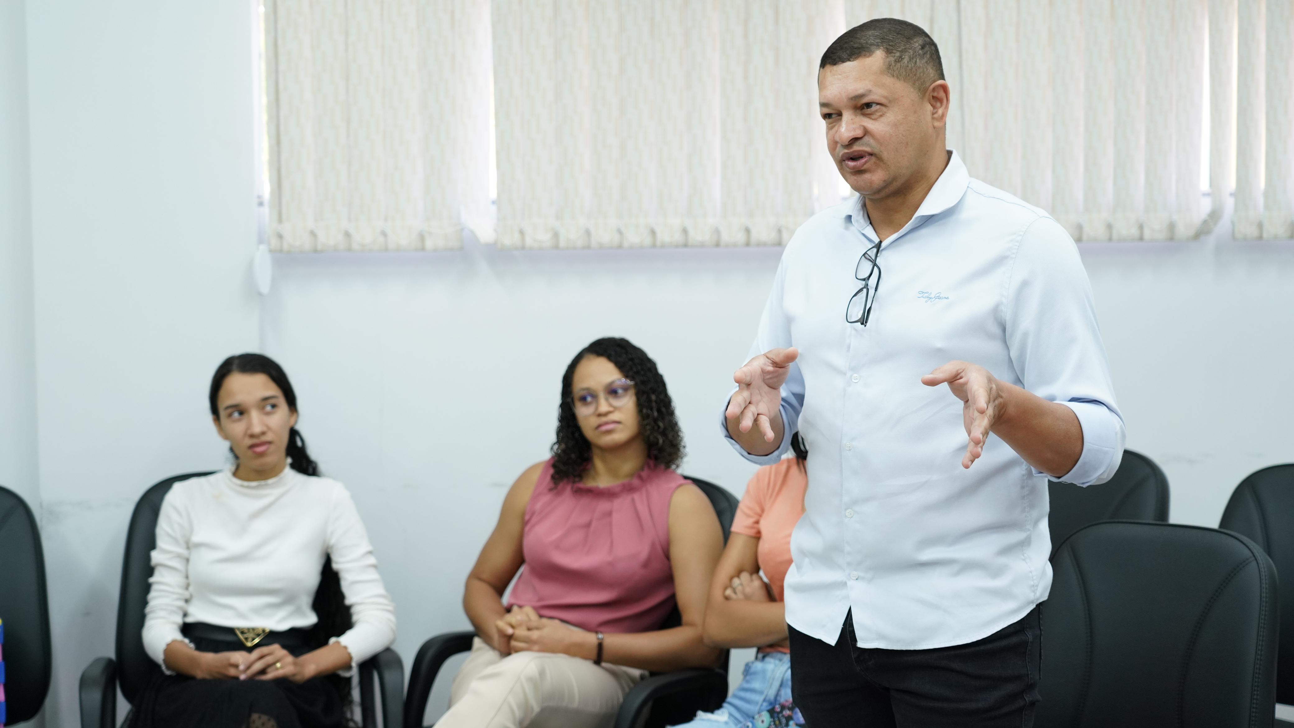 Fotografia colorida que mostra um homem moreno falando e gesticulando. 