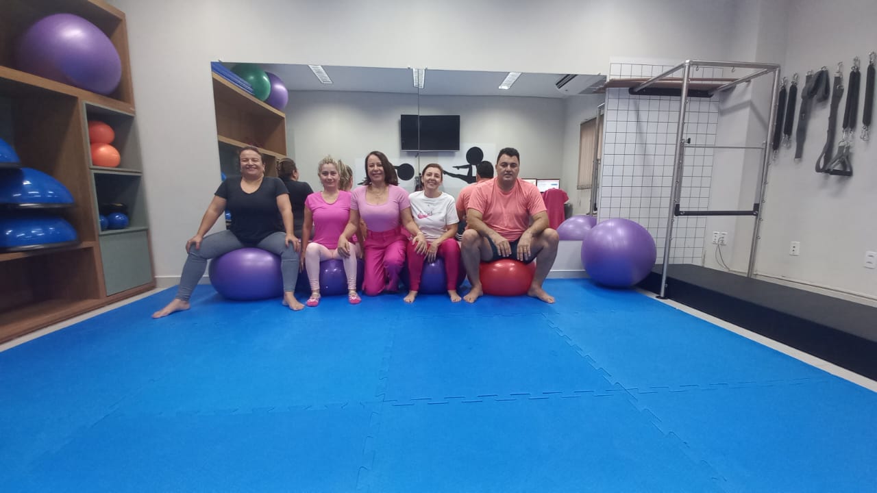 Homens e mulheres sentados em bolas e num tatame descansam depois do mat pilates