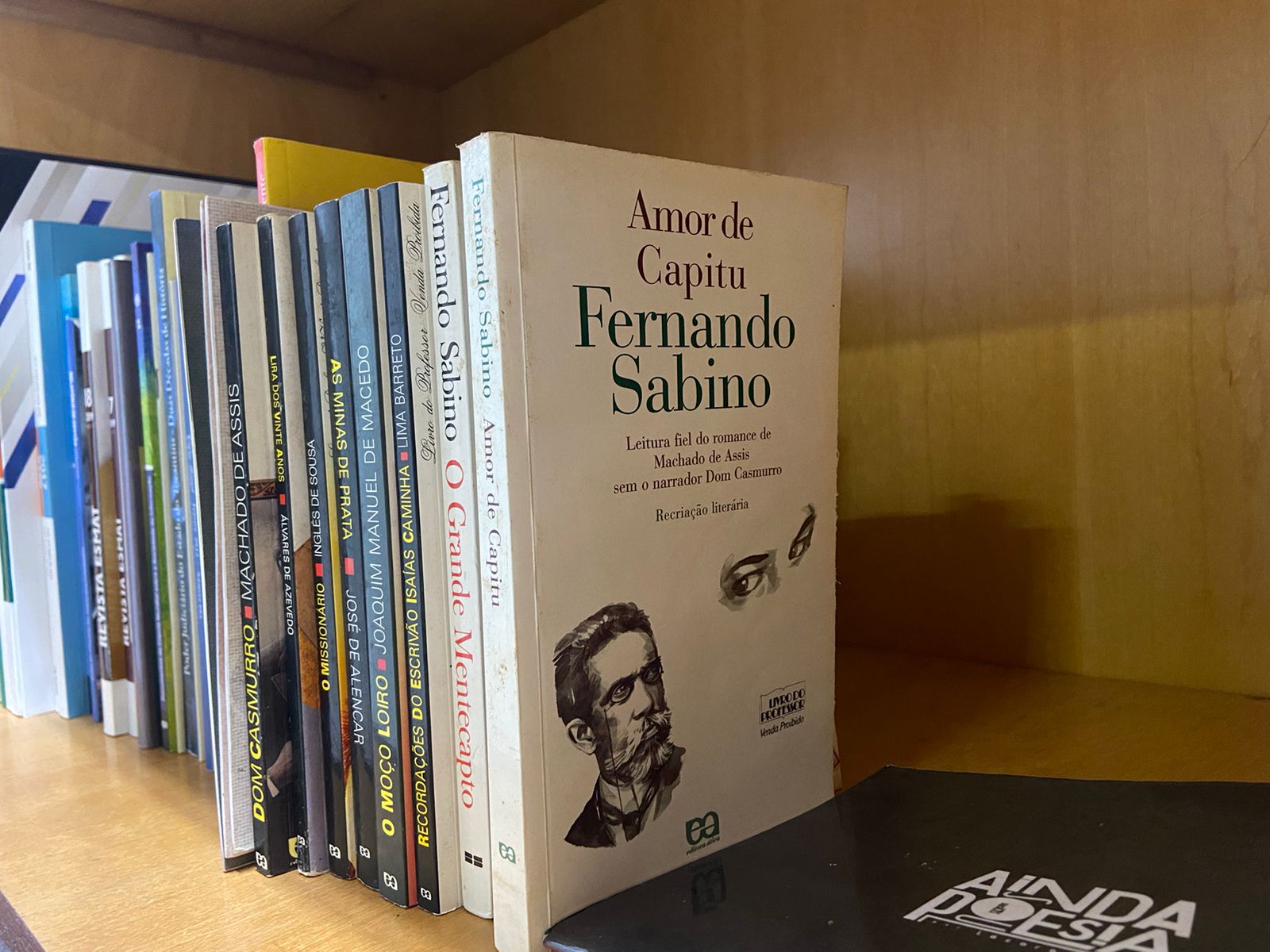 Fotografia colorida que mostra vários livros empilhados em uma prateleira