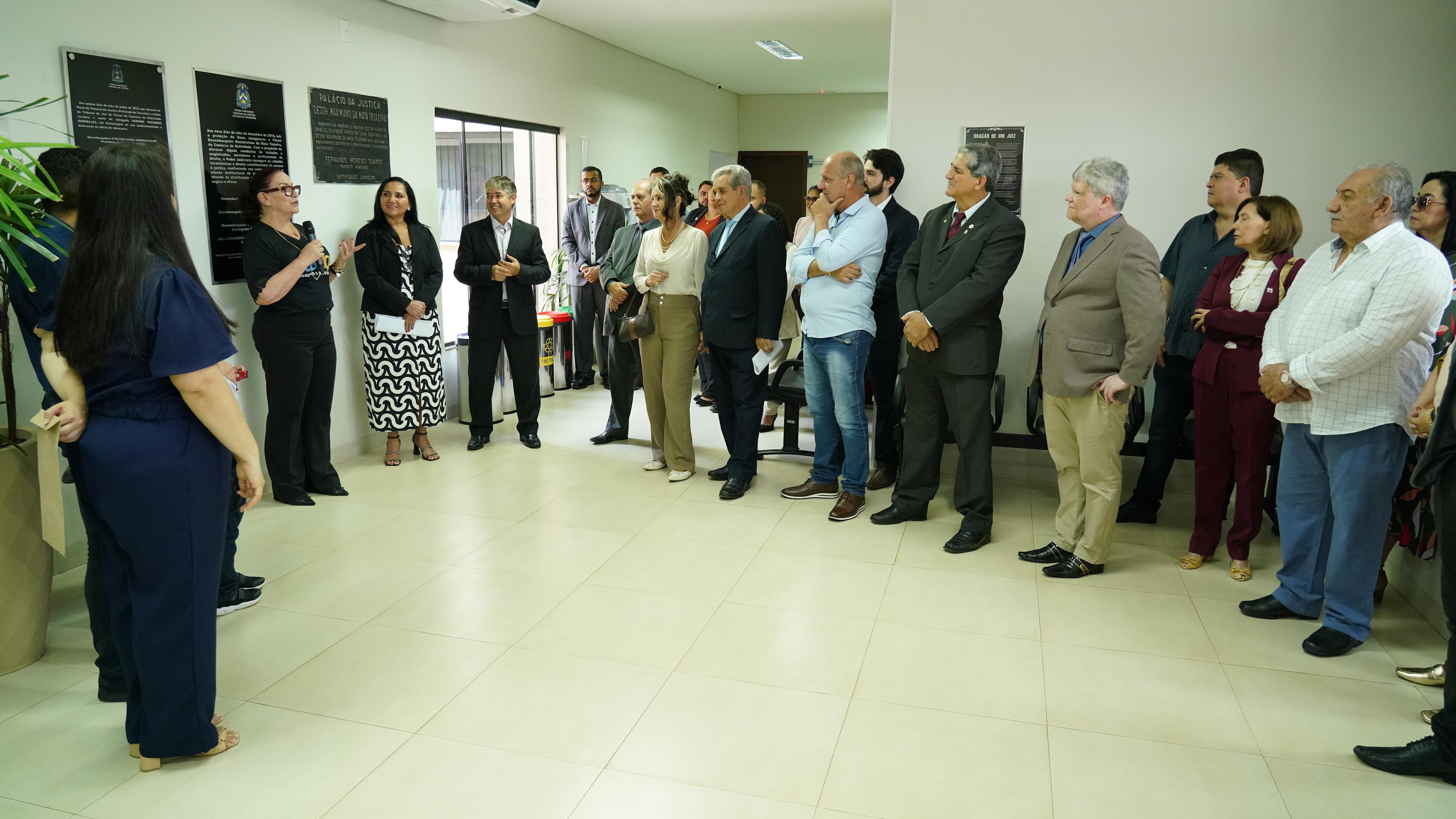 Pessoas em pé em uma roda ouvem a presidente do TJT falar em microfone