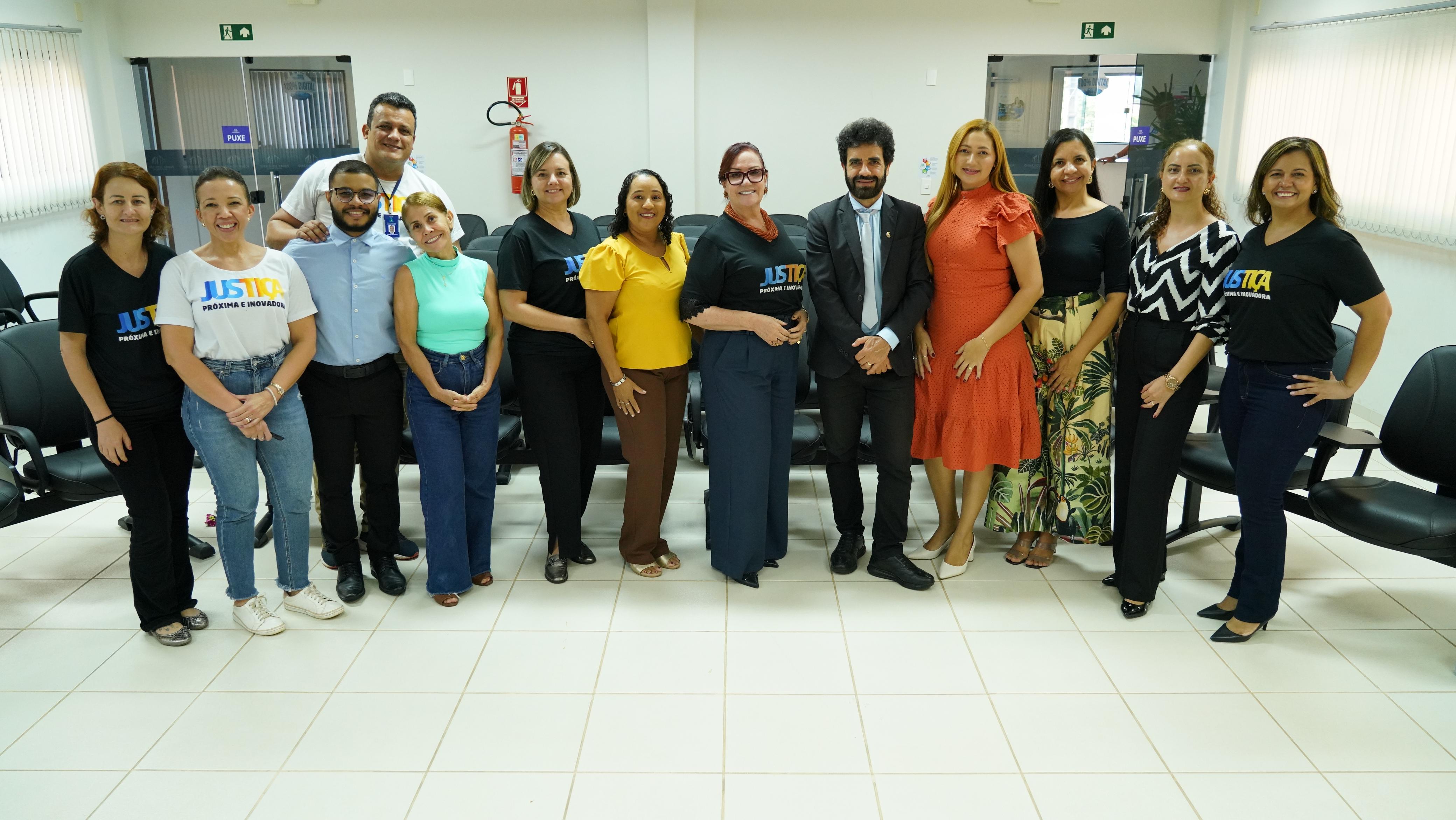 foto coloria horizontal mostra treze pessoas, homens e mulheres, no salao do juri do forum de xambioá