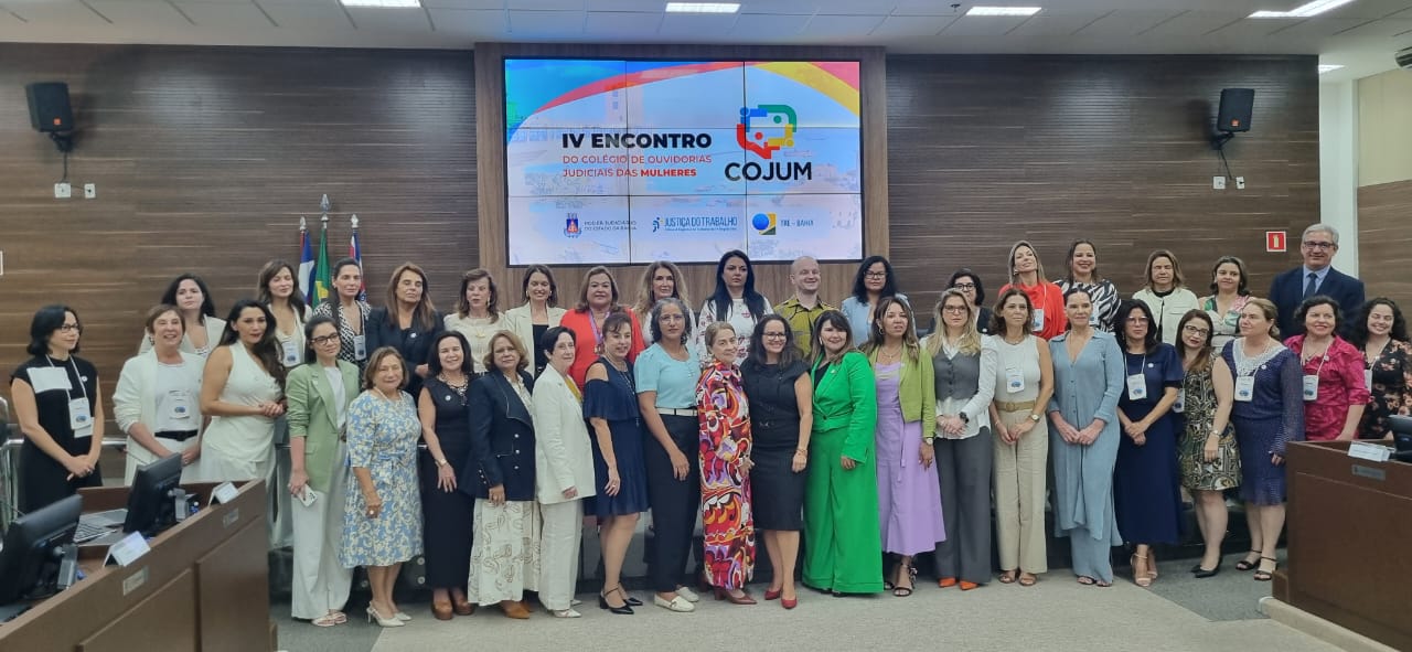 Fotografia colorida que mostra dezenas de mulheres em pé, posando para a imagem em uma sala fechada. Elas sorriem para câmera