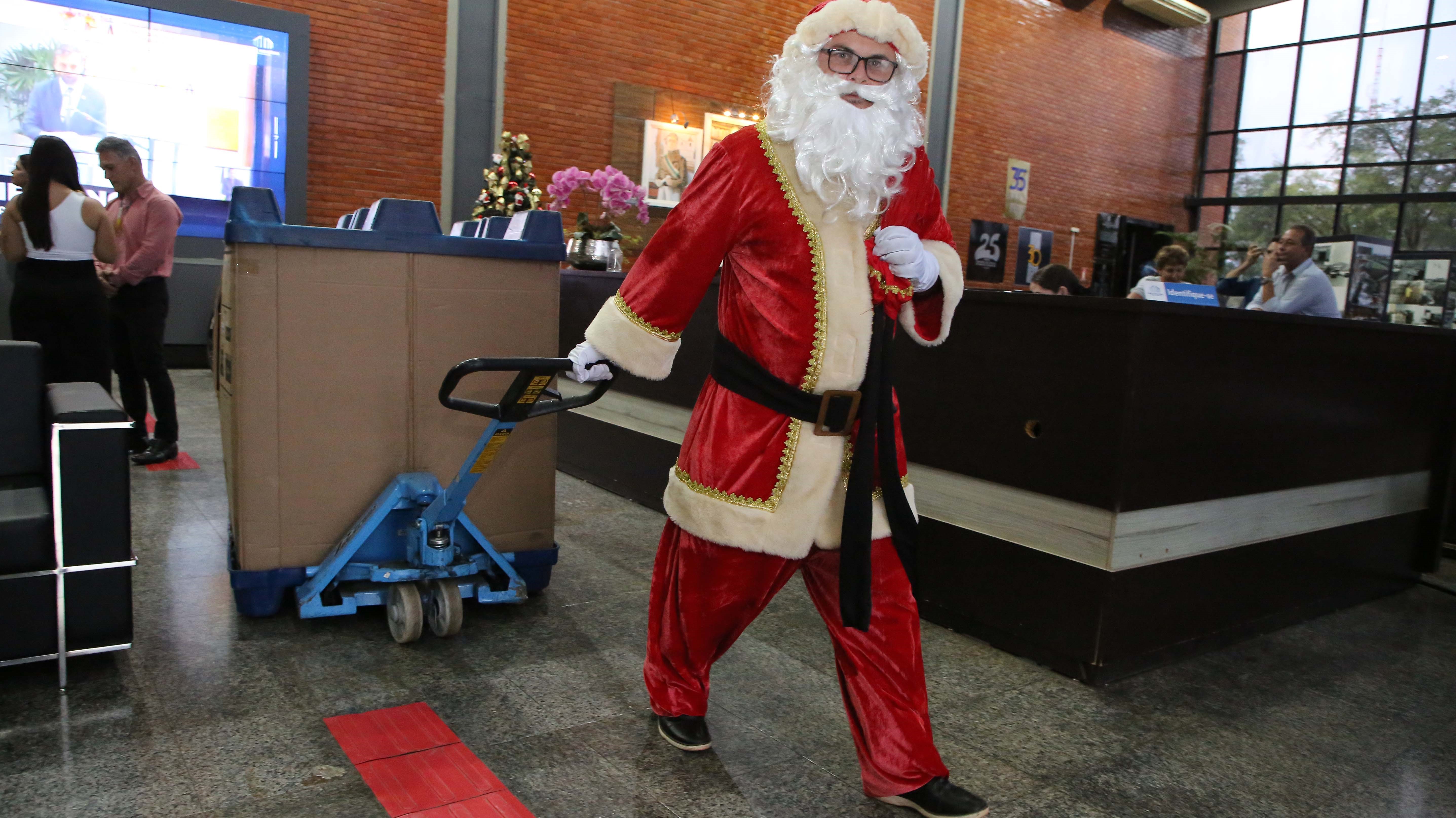 Imagem colorida que mostra o papai noel arrastando uma grande caixa cheia de brinquedos 
