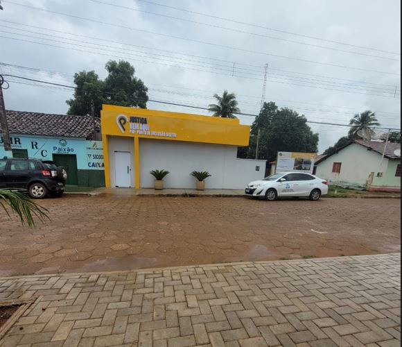 Foto de prédio branco com testeira amarela com carro branco parado em frente