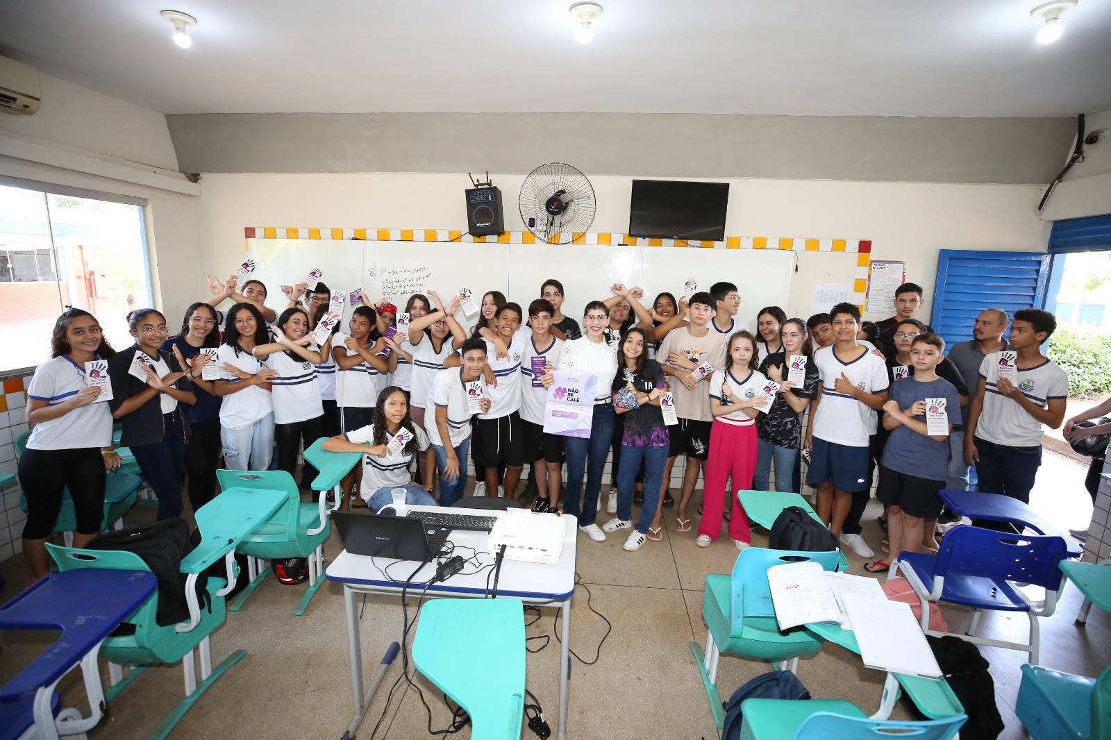Imagem mostra uma grande turma de estudantes reunida em uma sala de aula, participando de uma atividade educativa.
