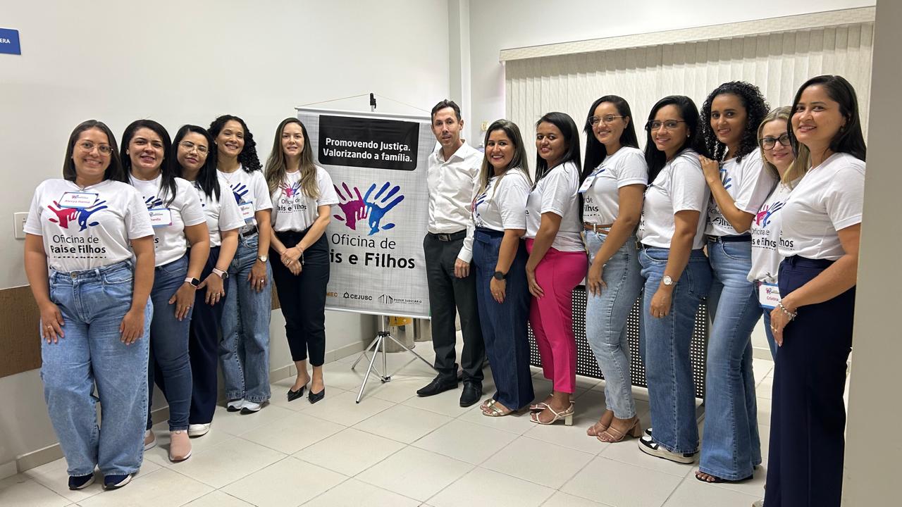 Juiz Fabiano com a equipe que trabalhou na oficina em Araguaçu. Na foto, 12 pessoas, sendo o juíz e 11 mulheres vestidas com camiseta branca com a logo e nome: Oficina de Pais e Filhos; ao centro um banner btanco da oficina