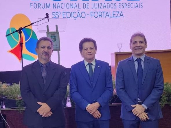 Três homens de terno em pé com de braços cruzados 