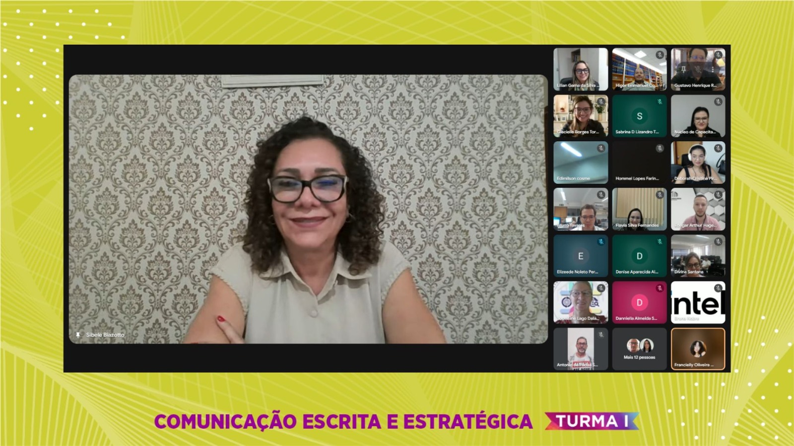 Imagem de uma tela de videoconferência. No quadro principal, ao centro, aparece uma mulher de pele clara, com cabelos cacheados e curtos, óculos de grau grandes e camisa sem mangas na cor clara. À direita, em miniaturas, estão os demais participantes da reunião, dispostos em uma grade de videoconferência. Algumas câmeras estão ligadas, mostrando rostos, e outras exibem apenas iniciais ou imagens de perfil. Na parte inferior da tela, está escrito em letras maiúsculas: “COMUNICAÇÃO ESCRITA E ESTRATÉGICA – TURMA I.