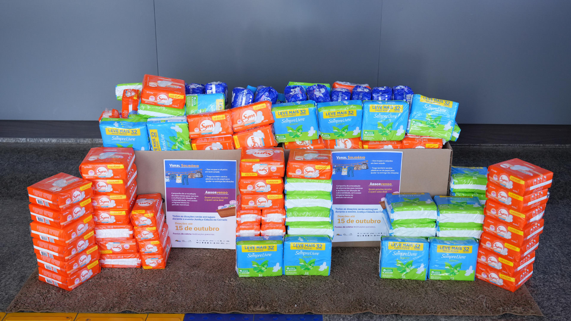 Vários pacotes de absorventes empilhados, organizados cuidadosamente, simbolizando o resultado expressivo da campanha “Absorvendo"