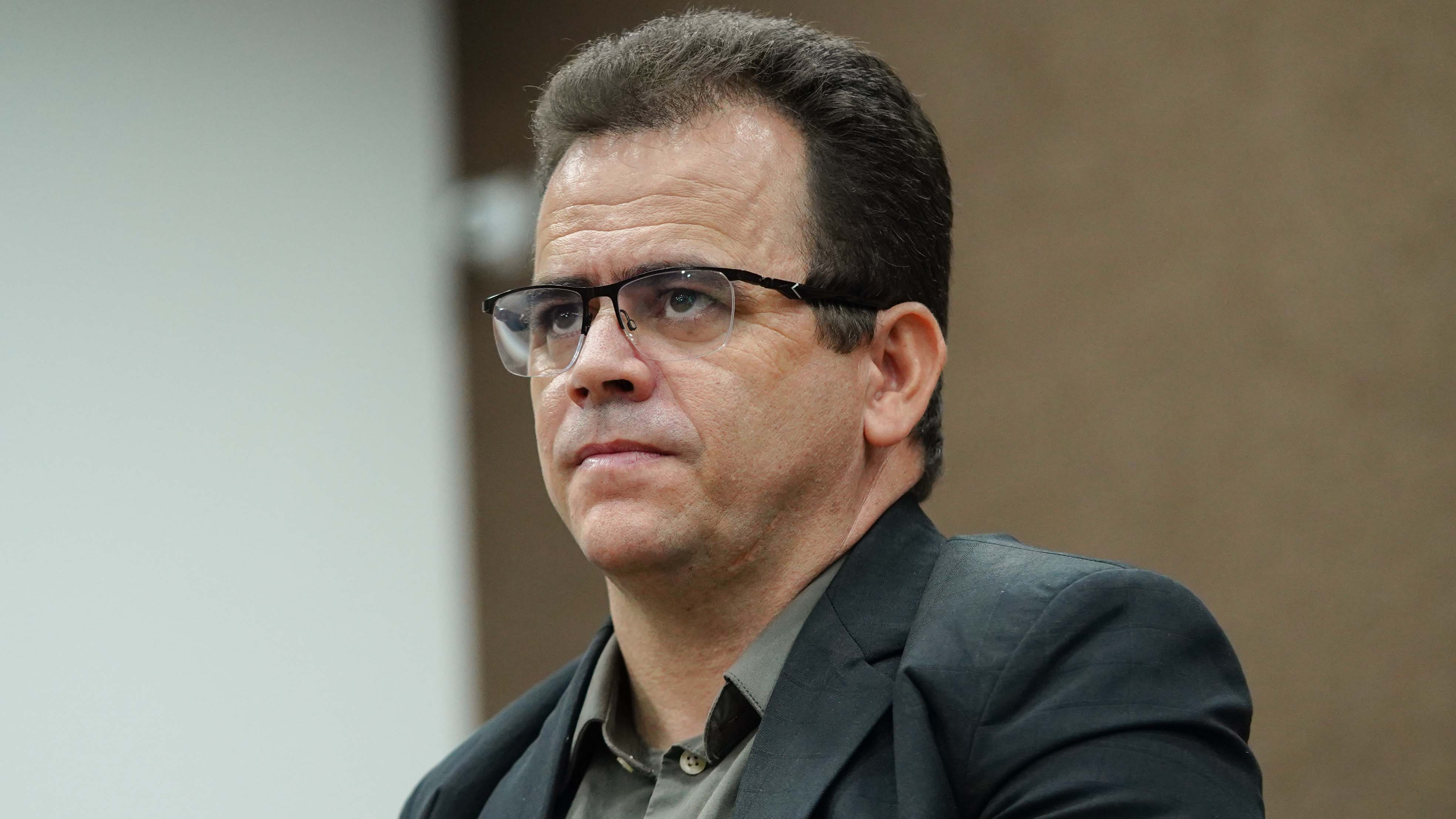 Juiz Fabiano Ribeiro, homem moreno, usa óculos e terno  e camisa cinza 