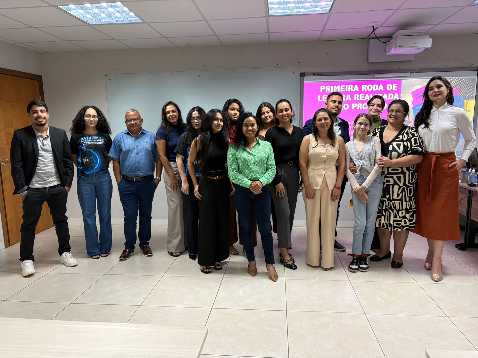 Foto de um grpo de mulheres, entre homens e mulheres, posam para foto