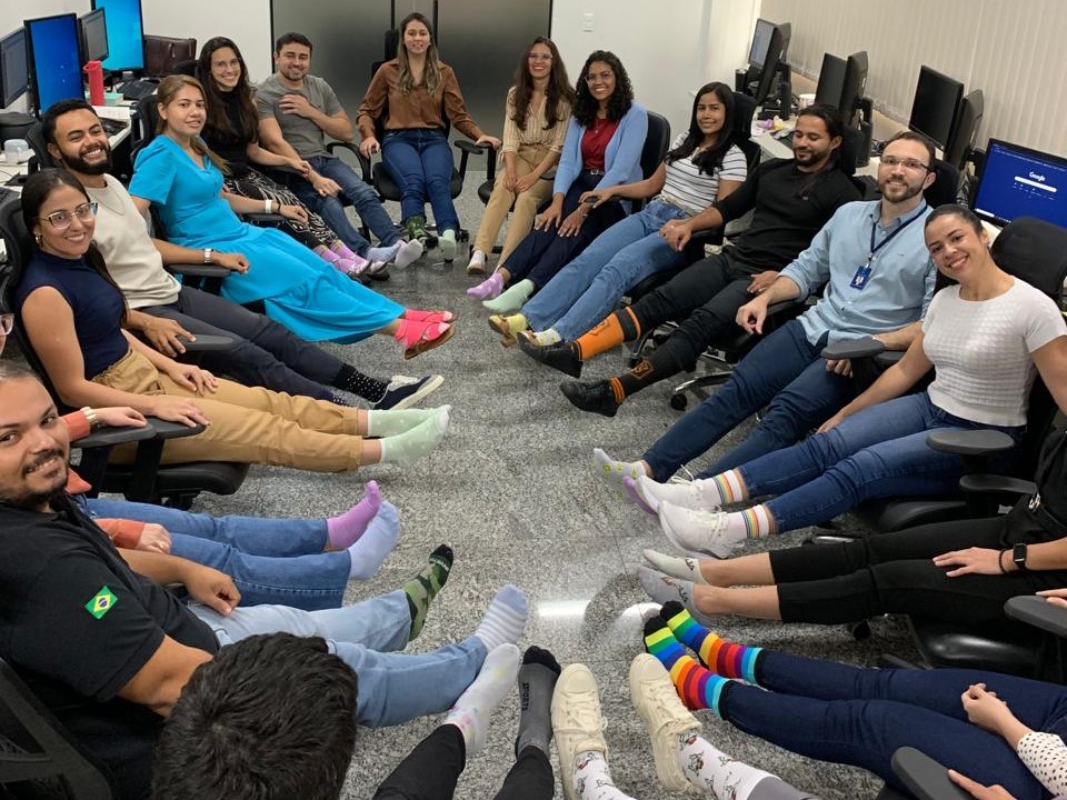 Na imagem aparecem várias pessoas sentadas em circulo, usando meias coloridas ou trocadas. A imagem mostra o engajamento do Poder Judiciário na Campanha de Inclusão das Pessoas com Síndrome de Down.