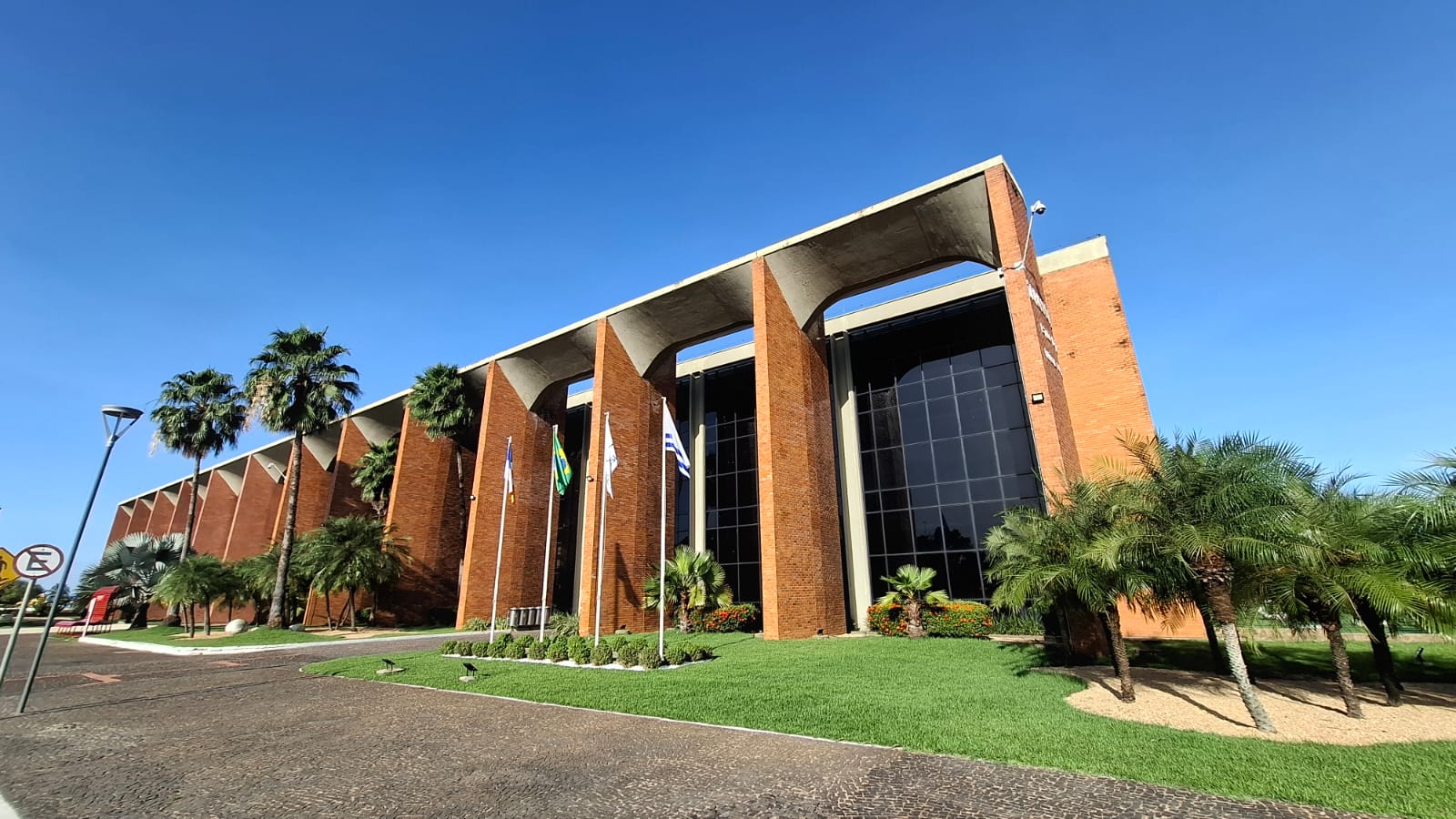 Fotografia colorida do prédio do Tribunal de Justiça do Tocantins. Ao fundo, o céu brilha claro em azul, e plantas estão em volta 
