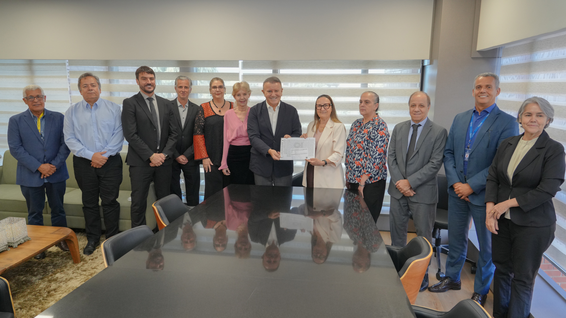 Autoridades do Judiciário e do Executivo posam para registro institucional durante a formalização da doação de área para ampliação do Fórum de Palmas. Ao centro, a presidente do TJTO, desembargadora Maysa Vendramini Rosal, e o prefeito de Palmas, Eduardo Siqueira Campos, exibem o documento oficial, cercados por magistrados, gestores e servidores que participaram do ato.