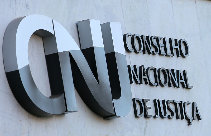 A imagem mostra a fachada do Conselho Nacional de Justiça (CNJ), com a sigla “CNJ” em destaque e o nome completo do órgão fixado na parede